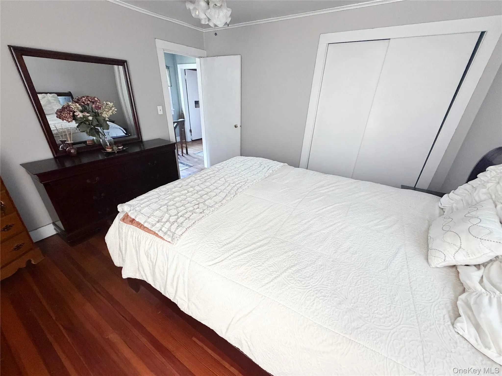 Hardwood flooring throughout, featuring a built-in sliding closet, and a white interior door Hardwood flooring throughout, featuring a built-in sliding closet, and a white interior door