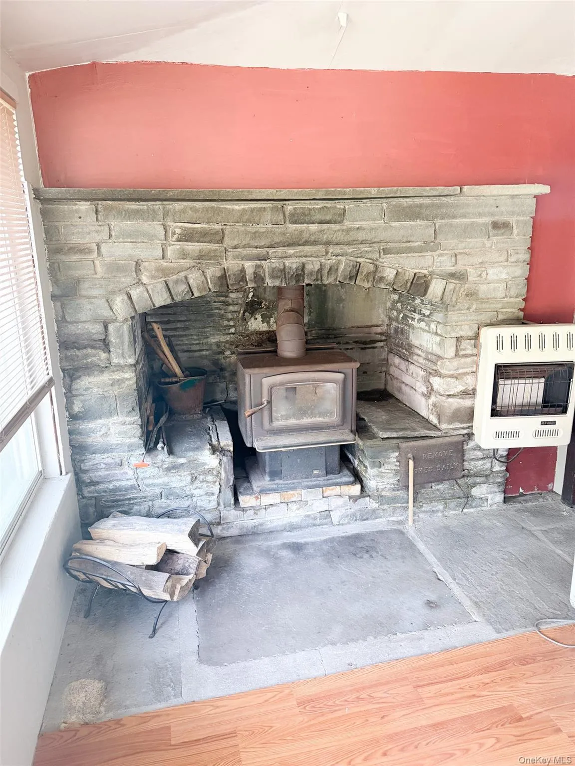 Stone fireplace with a wood-burning stove insert, an arched firebox, and a stone hearth Stone fireplace with a wood-burning stove insert, an arched firebox, and a stone hearth
