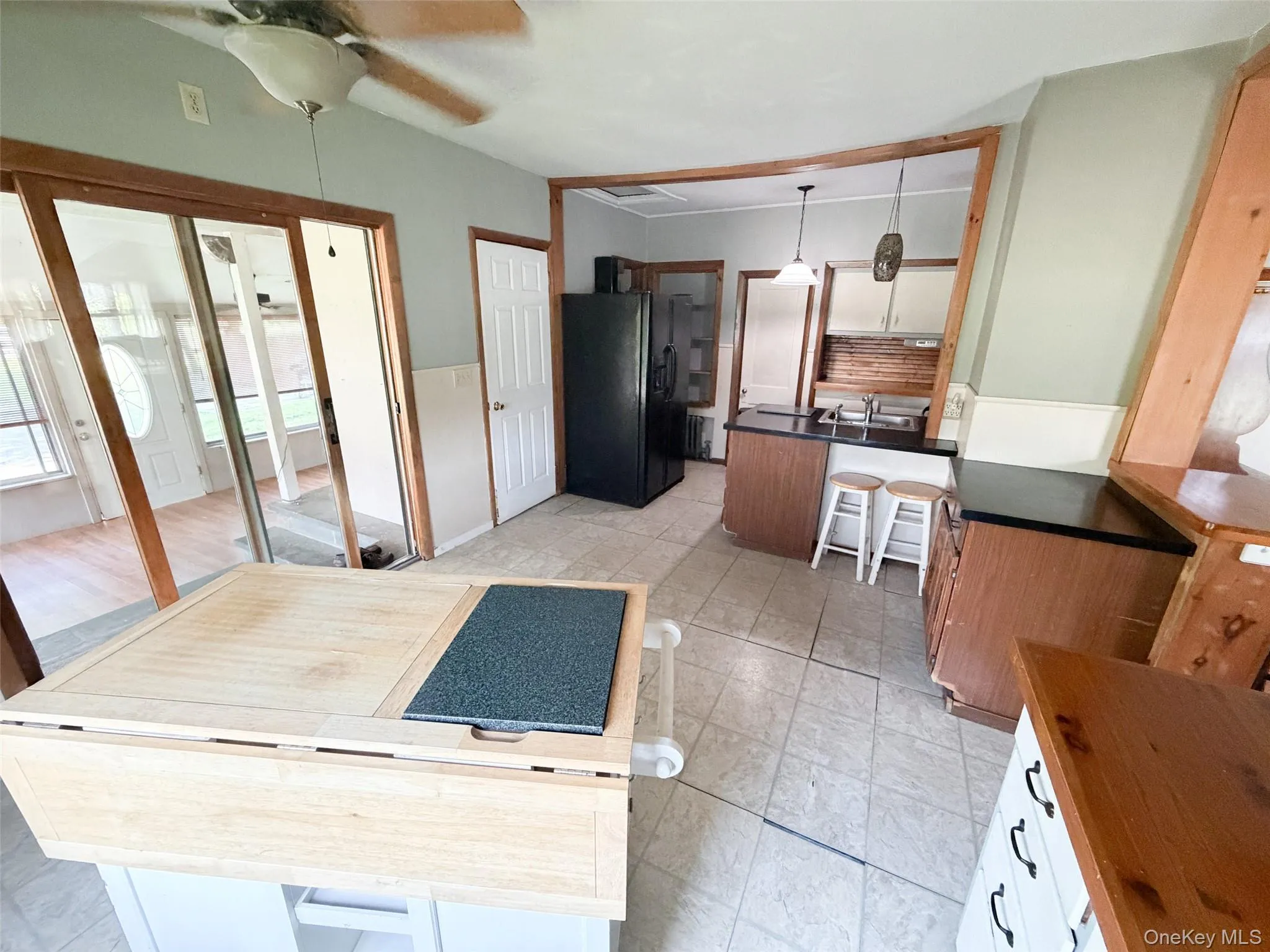 Kitchen featuring tile flooring, dark countertops, wood-finish cabinetry, and a ceiling fan Kitchen featuring tile flooring, dark countertops, wood-finish cabinetry, and a ceiling fan