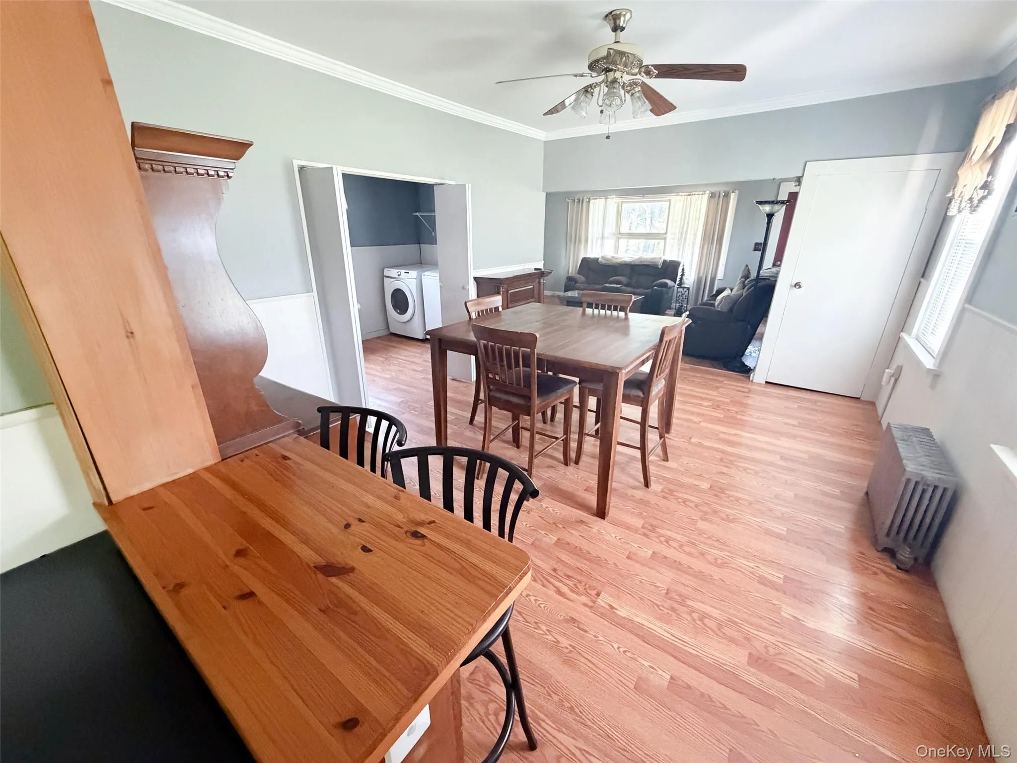 Spacious open-concept living area featuring wood-finish flooring, a ceiling fan with light fixture, and white trim Spacious open-concept living area featuring wood-finish flooring, a ceiling fan with light fixture, and white trim
