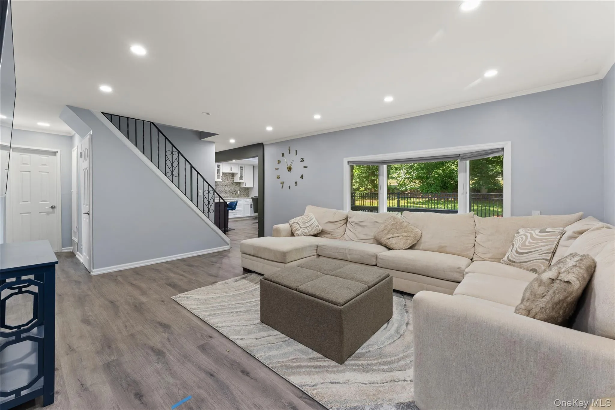 Spacious living area featuring wood-finish flooring, recessed lighting, and a prominent bay window Spacious living area featuring wood-finish flooring, recessed lighting, and a prominent bay window