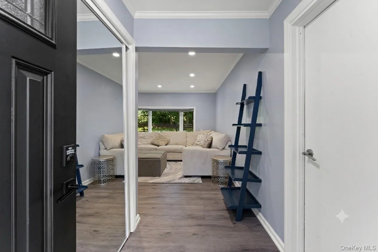 Entryway featuring wood-finish flooring, recessed lighting, and a full-length mirrored closet door Entryway featuring wood-finish flooring, recessed lighting, and a full-length mirrored closet door