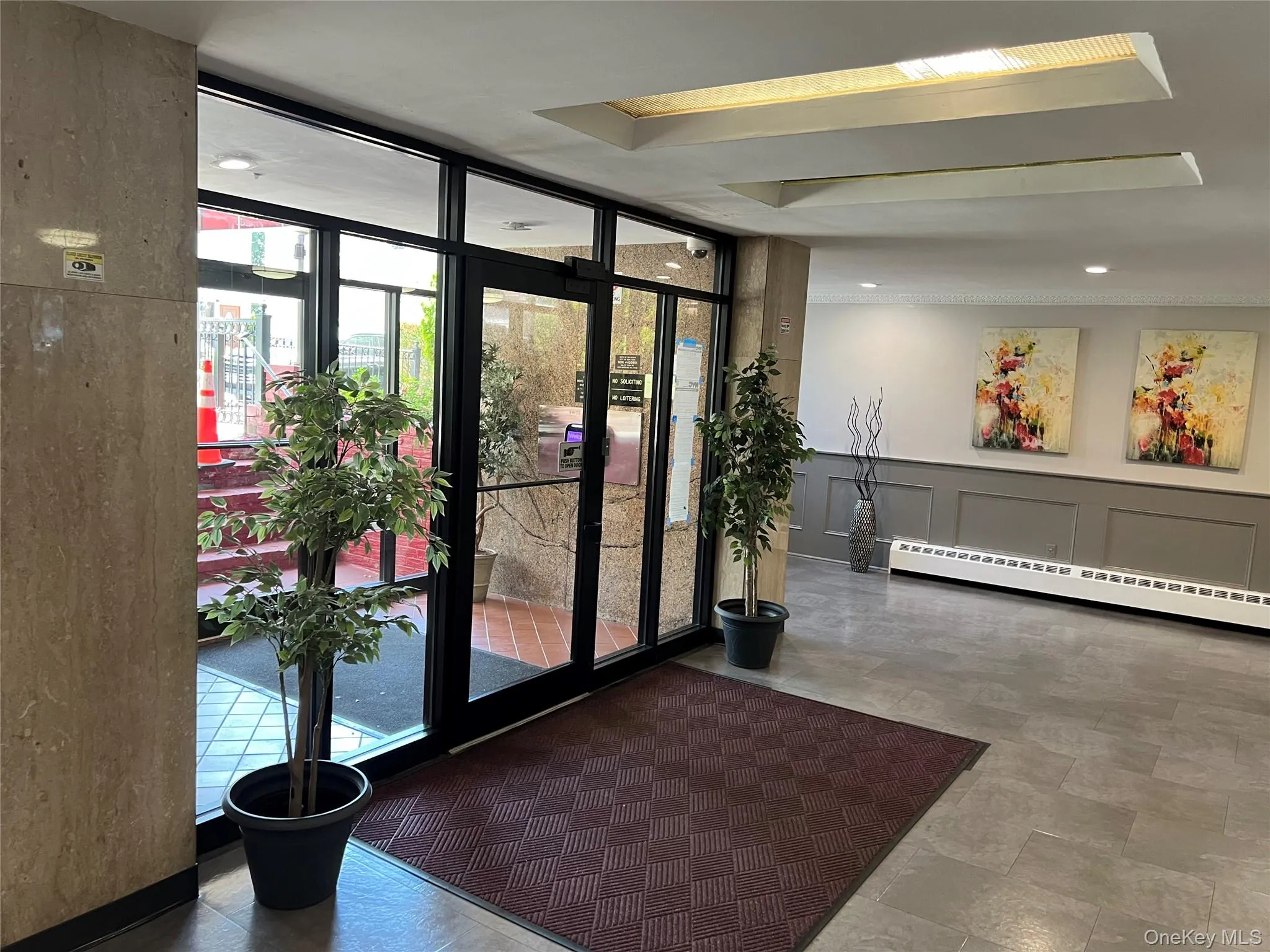 Building entryway featuring full-lite double doors, tile flooring, and wainscoting Building entryway featuring full-lite double doors, tile flooring, and wainscoting