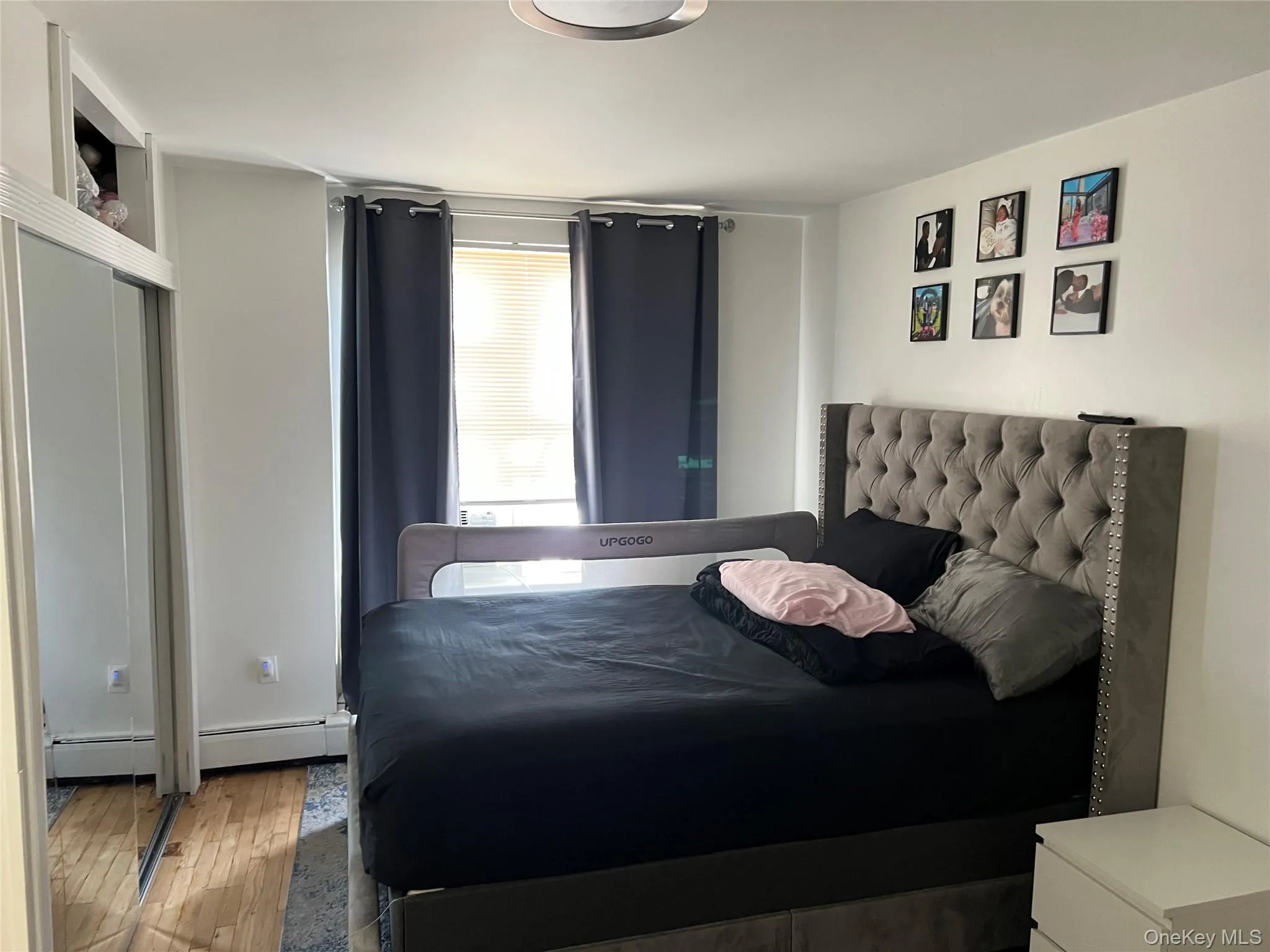 Bedroom featuring wood-finish flooring and white painted walls Bedroom featuring wood-finish flooring and white painted walls