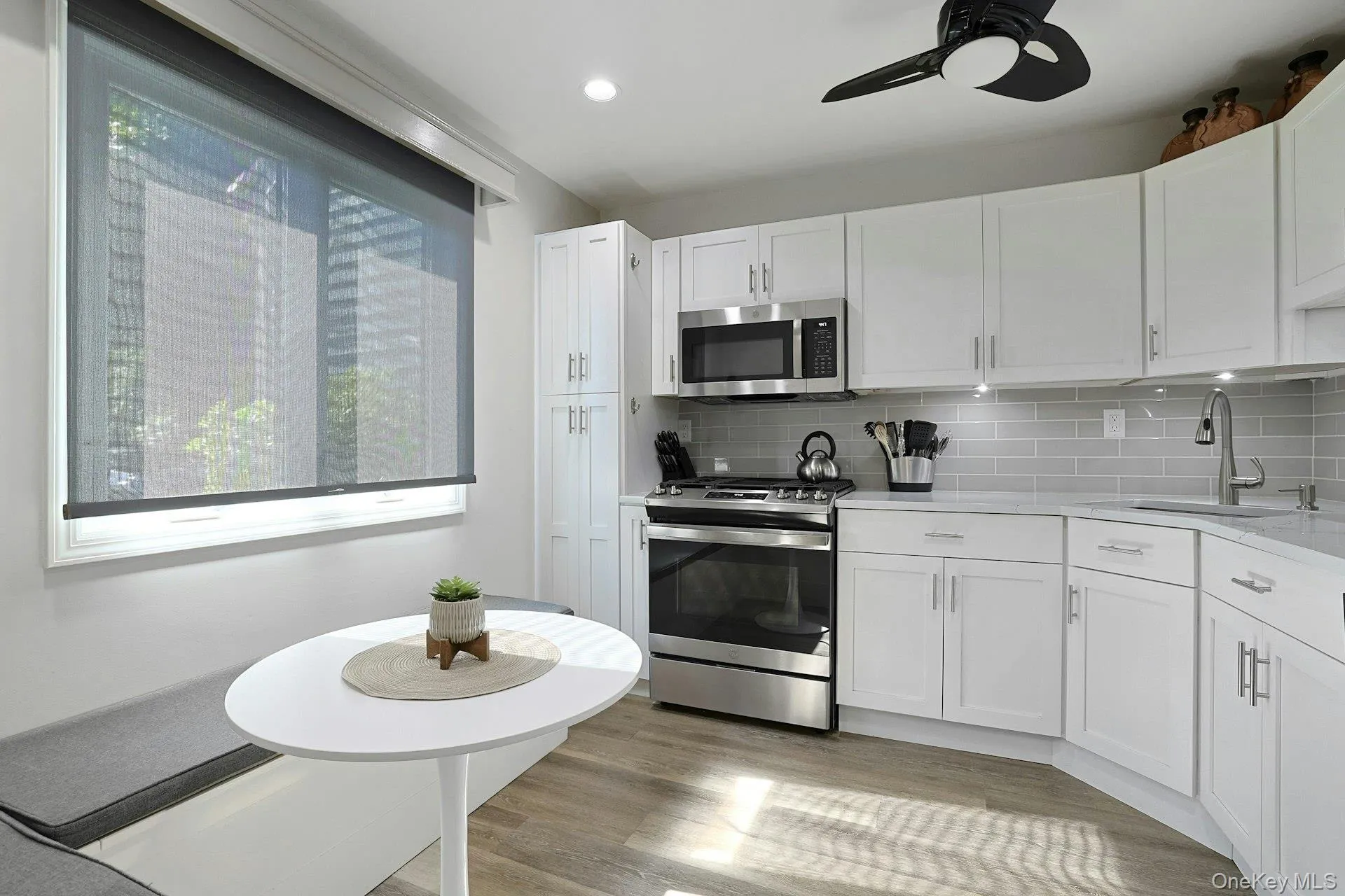 Bright updated kitchen featuring white cabinetry, SS appliances, quartz countertops, undercabinet lighting, and wood-finish flooring Bright updated kitchen featuring white cabinetry, SS appliances, quartz countertops, undercabinet lighting, and wood-finish flooring