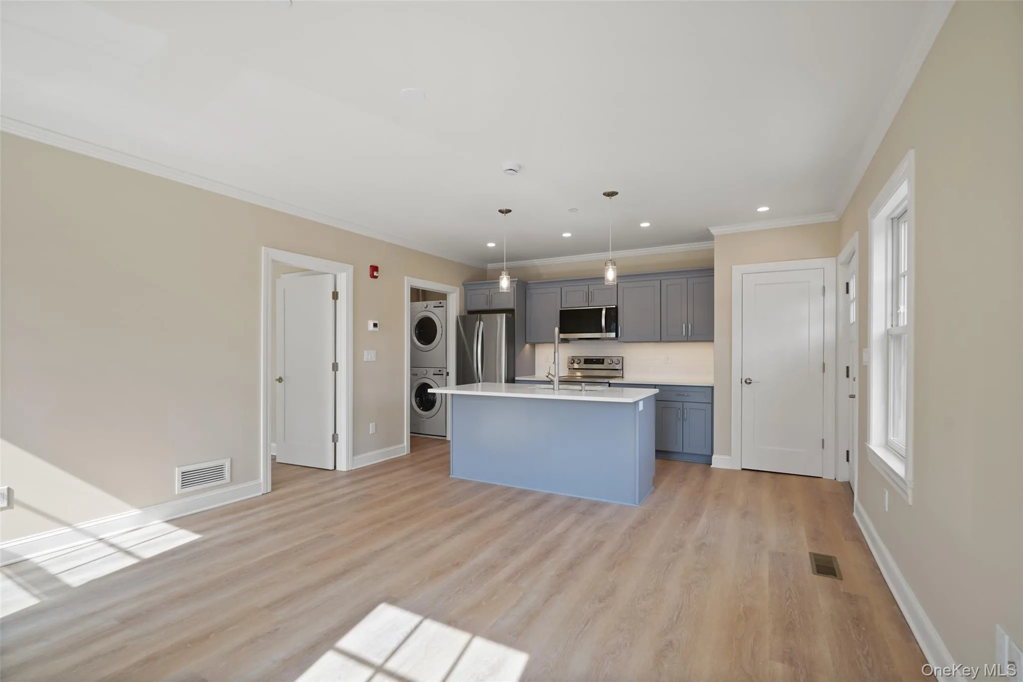 Kitchen with stainless steel appliances, gray cabinets, stacked washer and dryer Kitchen with stainless steel appliances, gray cabinets, stacked washer and dryer