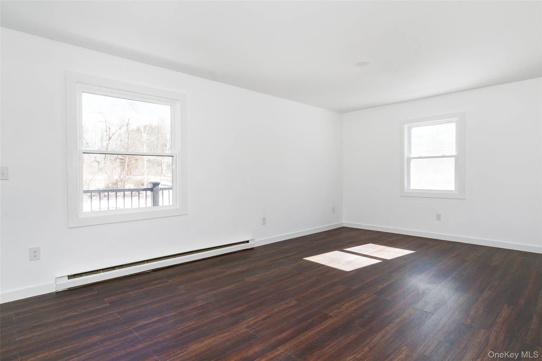 Unfurnished living room with a baseboard heating unit and dark hardwood / wood-style floors Unfurnished living room with a baseboard heating unit and dark hardwood / wood-style floors