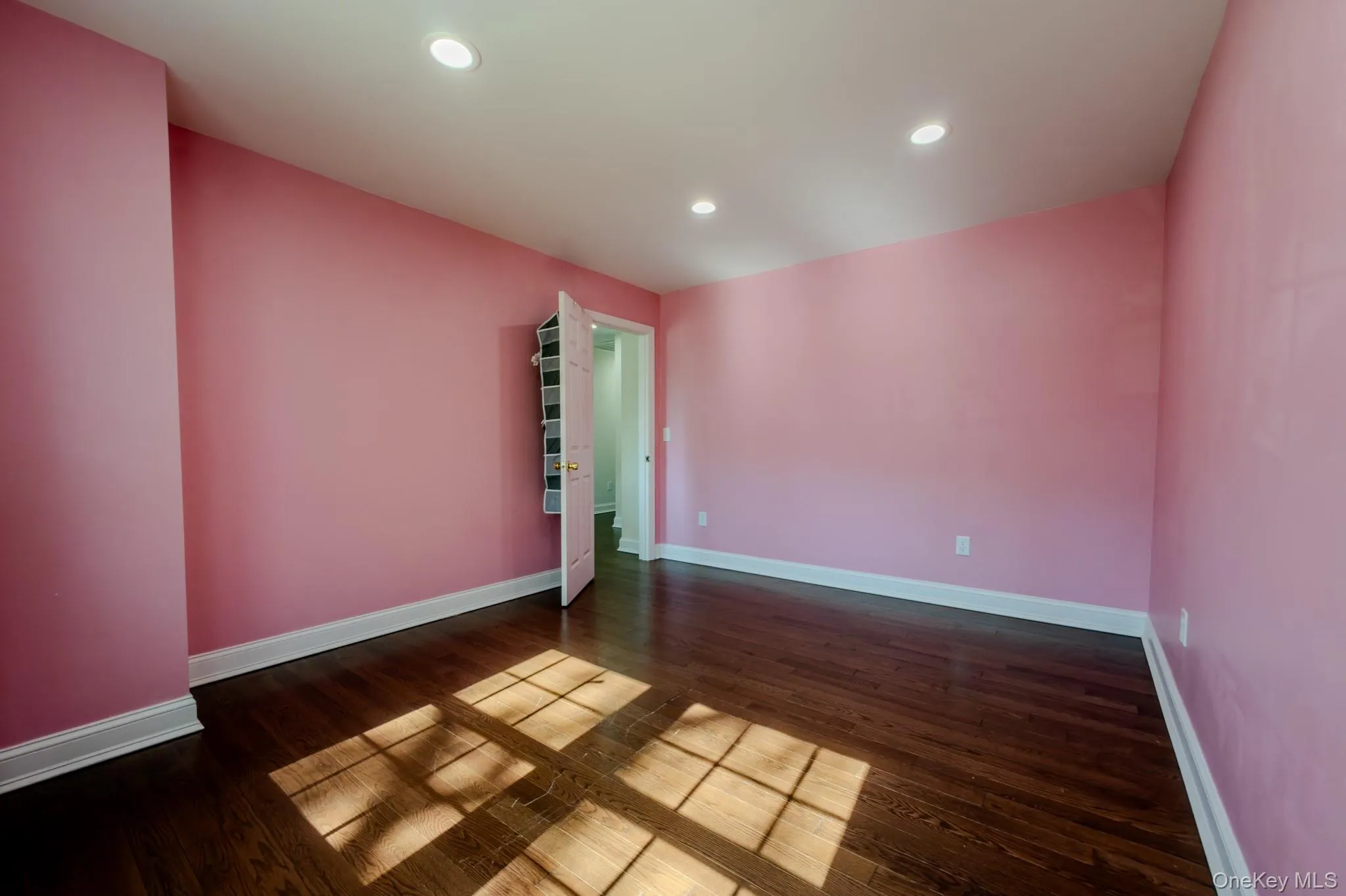 Spacious room featuring wood-finish flooring, recessed lighting, and white baseboards Spacious room featuring wood-finish flooring, recessed lighting, and white baseboards