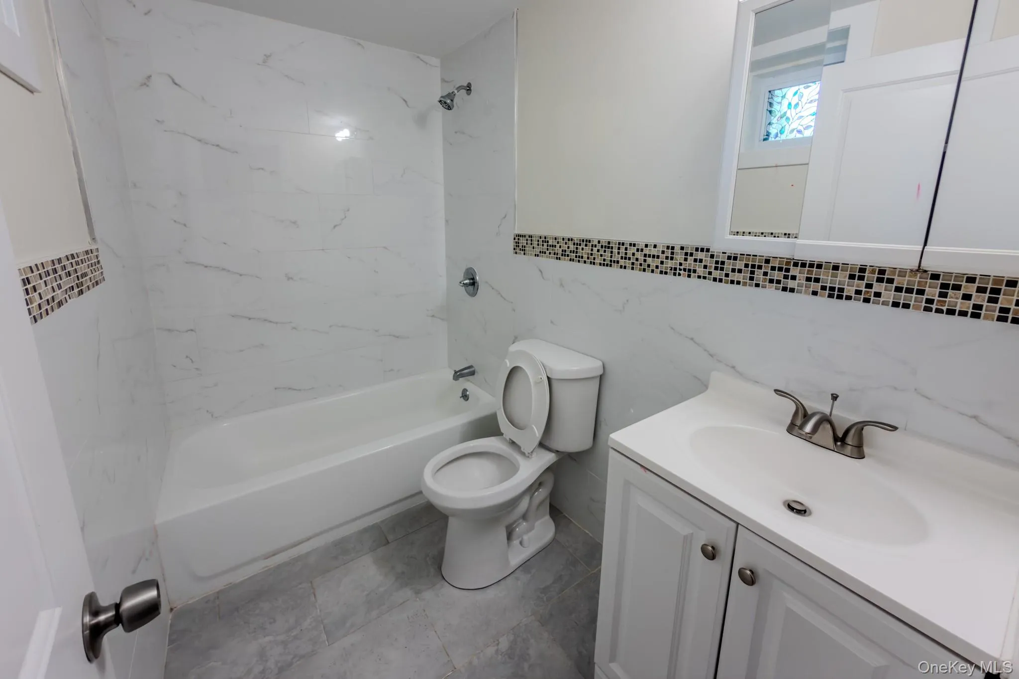 Bathroom featuring a white vanity with integrated sink, brushed nickel faucet, and a wall-mounted mirrored medicine cabinet Bathroom featuring a white vanity with integrated sink, brushed nickel faucet, and a wall-mounted mirrored medicine cabinet