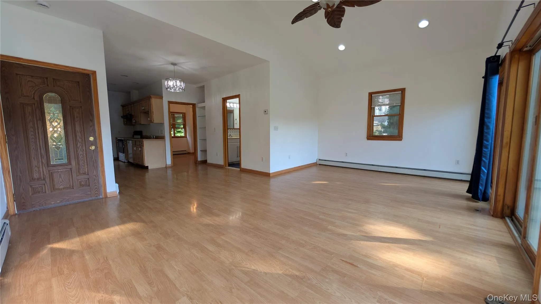 Unfurnished living room featuring a baseboard heating unit, light wood finished floors, recessed lighting, ceiling fan, and healthy amount of natural light Unfurnished living room featuring a baseboard heating unit, light wood finished floors, recessed lighting, ceiling fan, and healthy amount of natural light