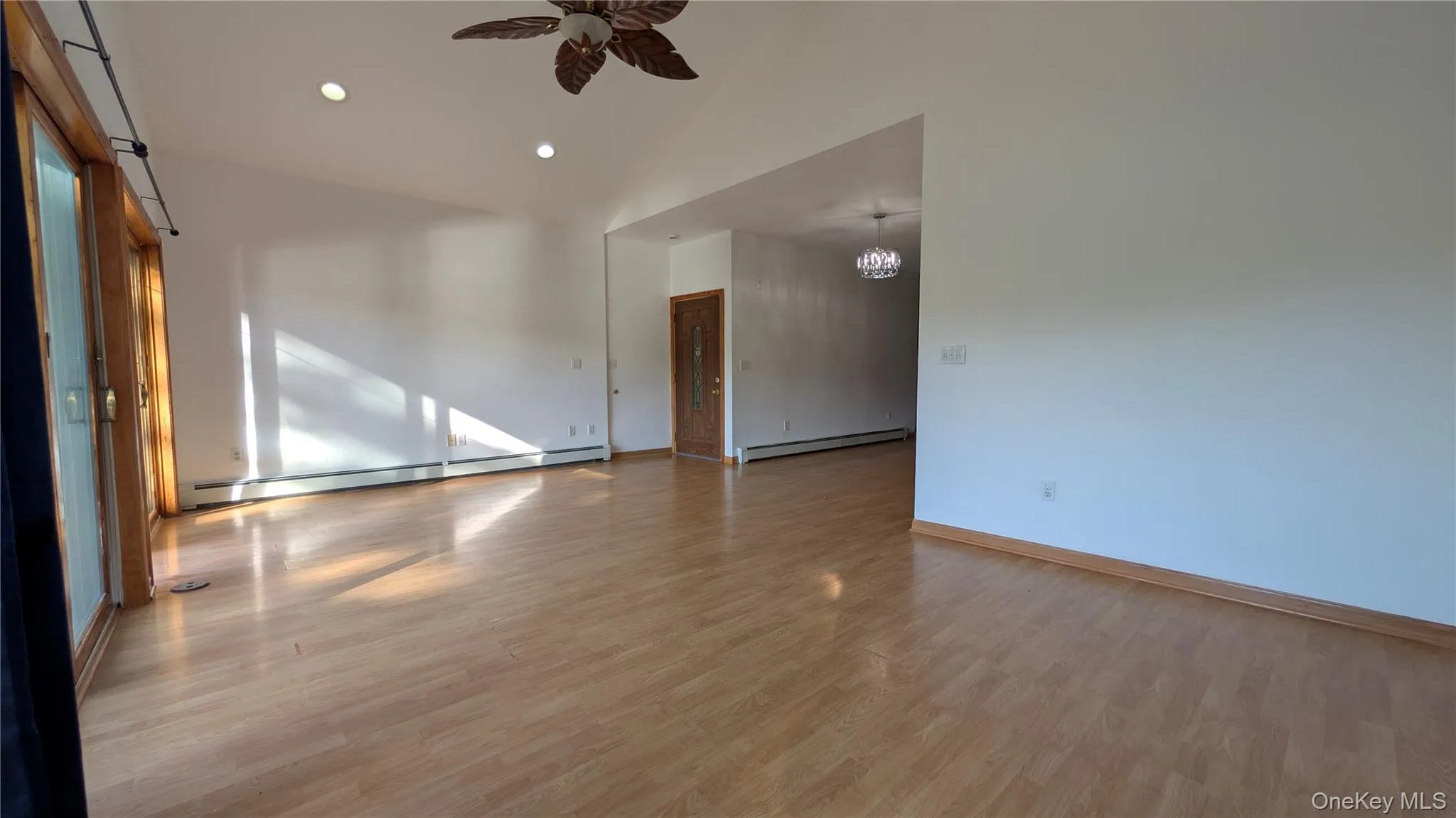 Empty room featuring light wood-style flooring, baseboard heating, recessed lighting, a ceiling fan, and a chandelier Empty room featuring light wood-style flooring, baseboard heating, recessed lighting, a ceiling fan, and a chandelier