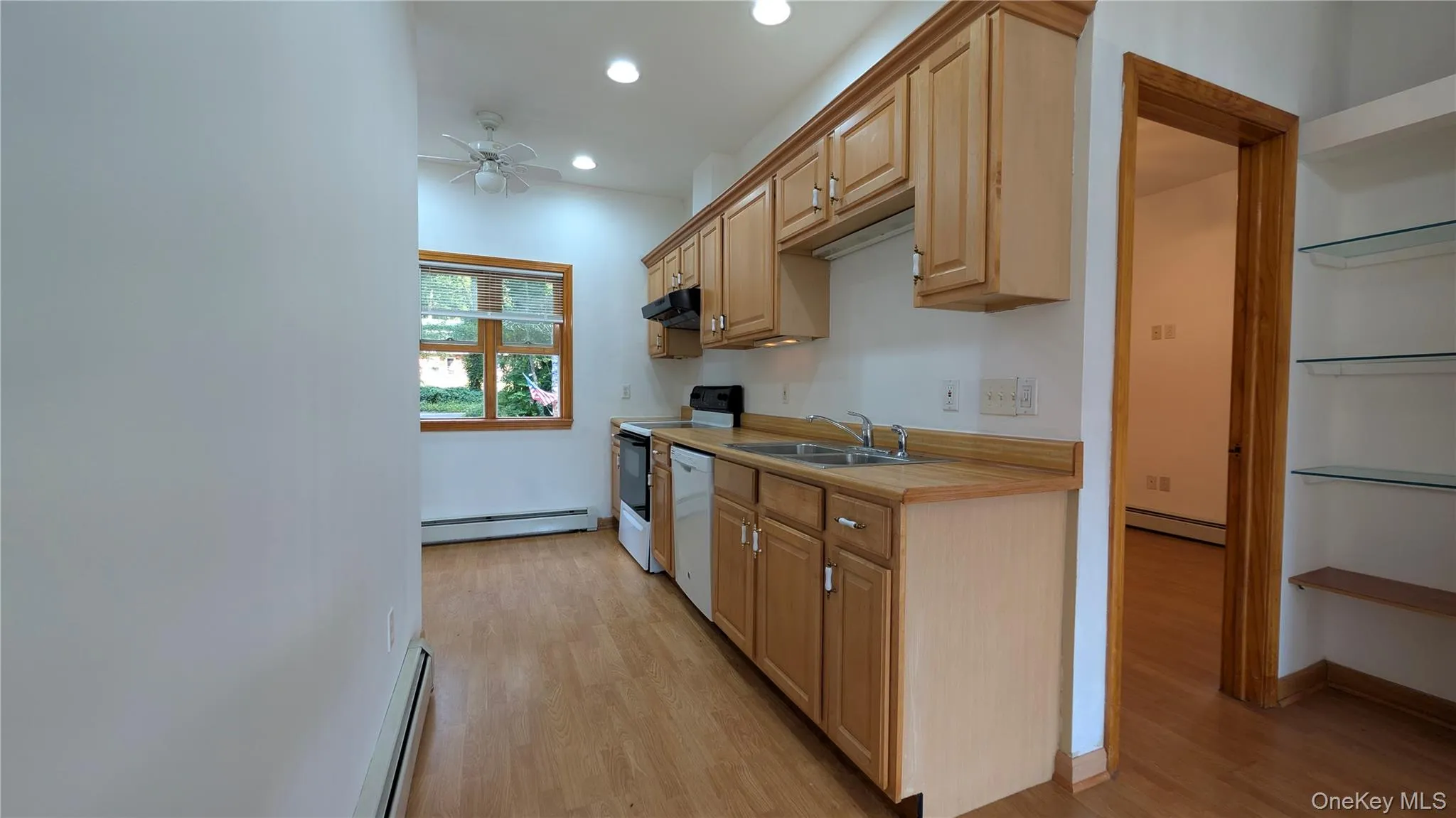 Kitchen with light countertops, recessed lighting, a baseboard heating unit, light wood-style floors, and white appliances Kitchen with light countertops, recessed lighting, a baseboard heating unit, light wood-style floors, and white appliances