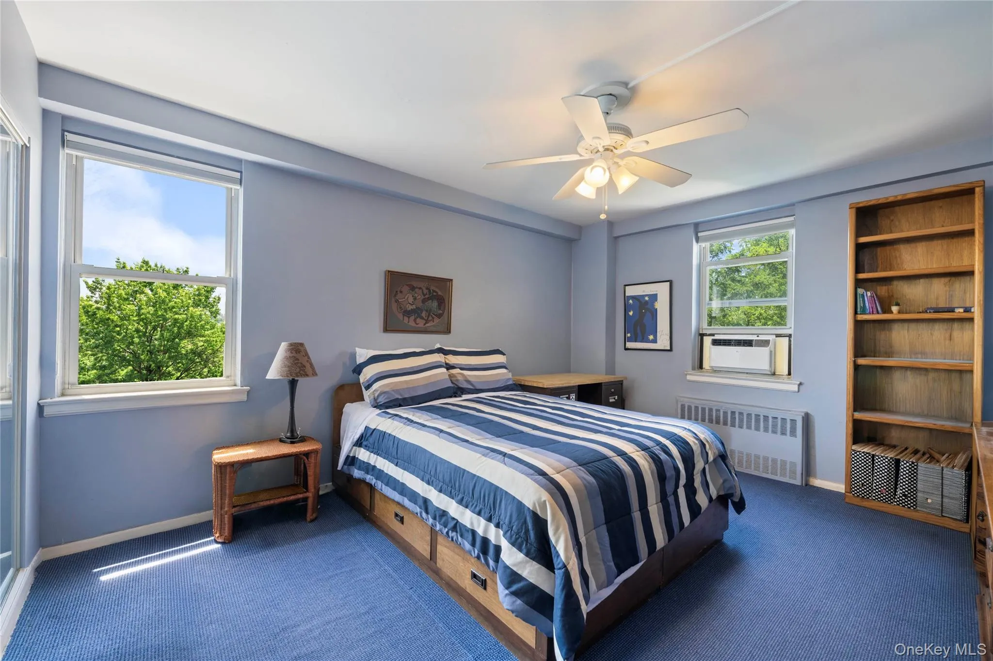 Bedroom featuring blue wall paint, blue carpeting, and multiple windows Bedroom featuring blue wall paint, blue carpeting, and multiple windows