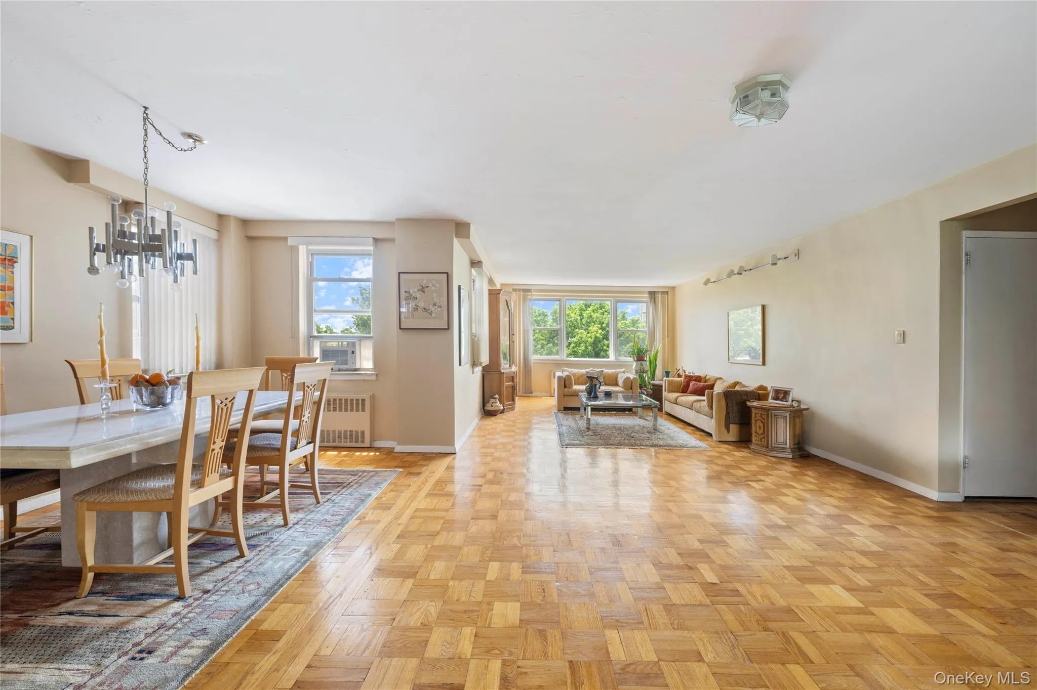 Spacious open-concept living and dining areas featuring parquet wood flooring throughout Spacious open-concept living and dining areas featuring parquet wood flooring throughout