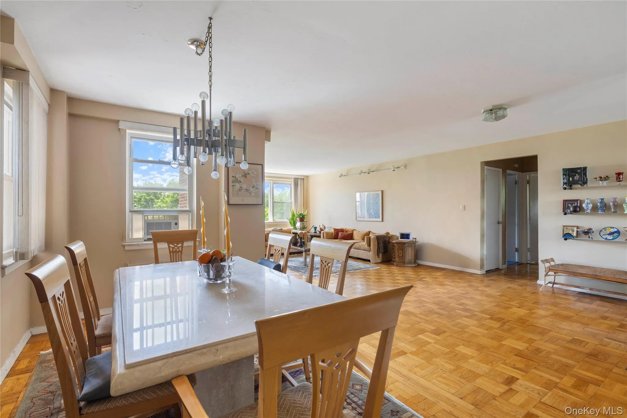 Dining area featuring a contemporary chandelier, large windows with natural light, and parquet wood flooring Dining area featuring a contemporary chandelier, large windows with natural light, and parquet wood flooring