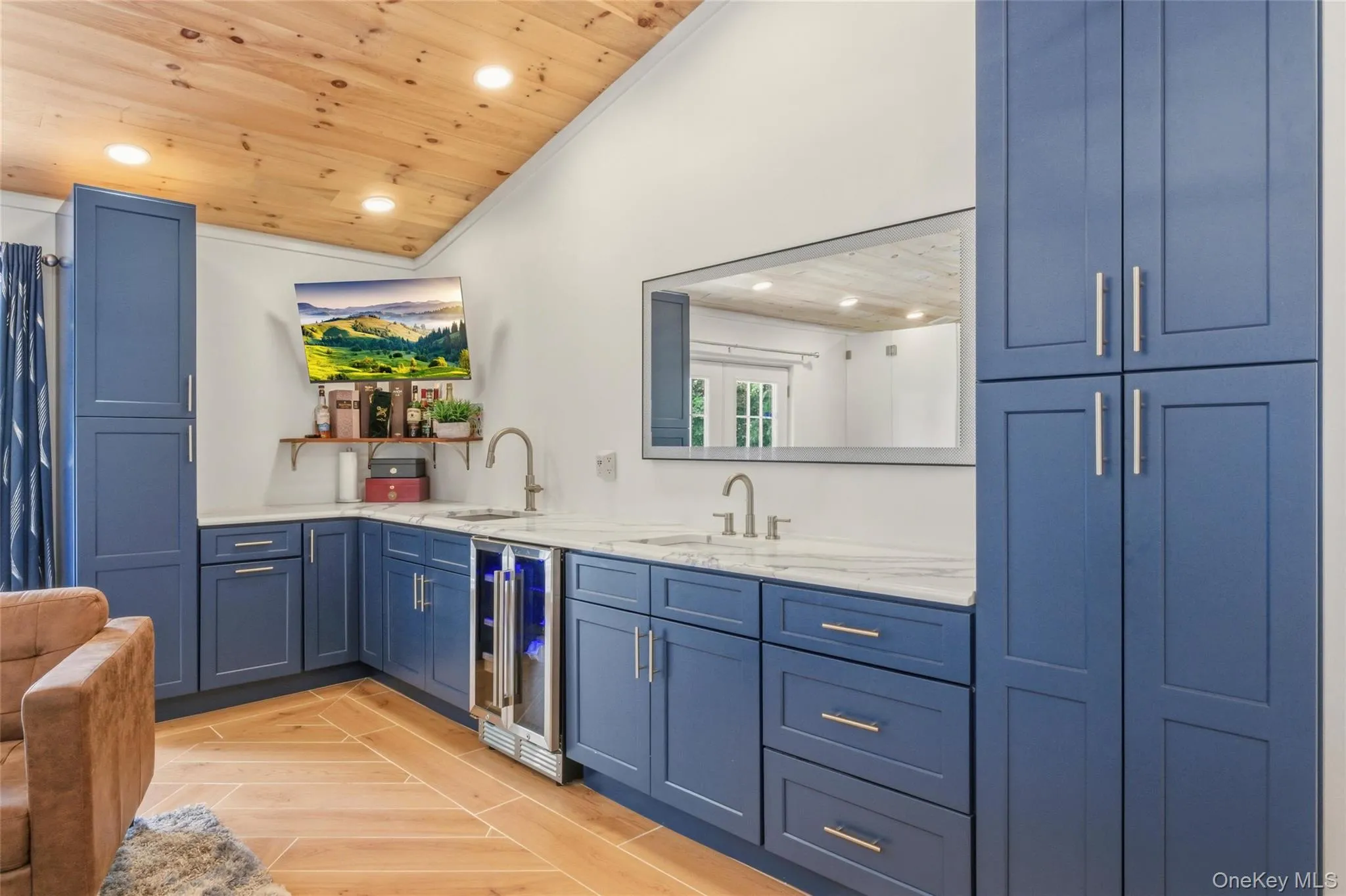This sleek wet bar showcases blue cabinetry, quartz countertops, and dual stainless-steel sinks for a polished, modern aesthetic. A built-in beverage fridge and wall-mounted TV make it perfect for entertaining or relaxing. This sleek wet bar showcases blue cabinetry, quartz countertops, and dual stainless-steel sinks for a polished, modern aesthetic. A built-in beverage fridge and wall-mounted TV make it perfect for entertaining or relaxing.