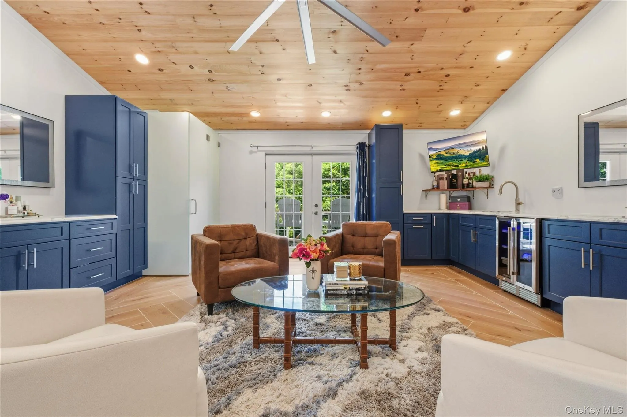 This inviting living space offers warm wood tones, bold navy cabinetry, and a cozy seating arrangement. A built-in wet bar and French doors enhance both style and functionality. This inviting living space offers warm wood tones, bold navy cabinetry, and a cozy seating arrangement. A built-in wet bar and French doors enhance both style and functionality.