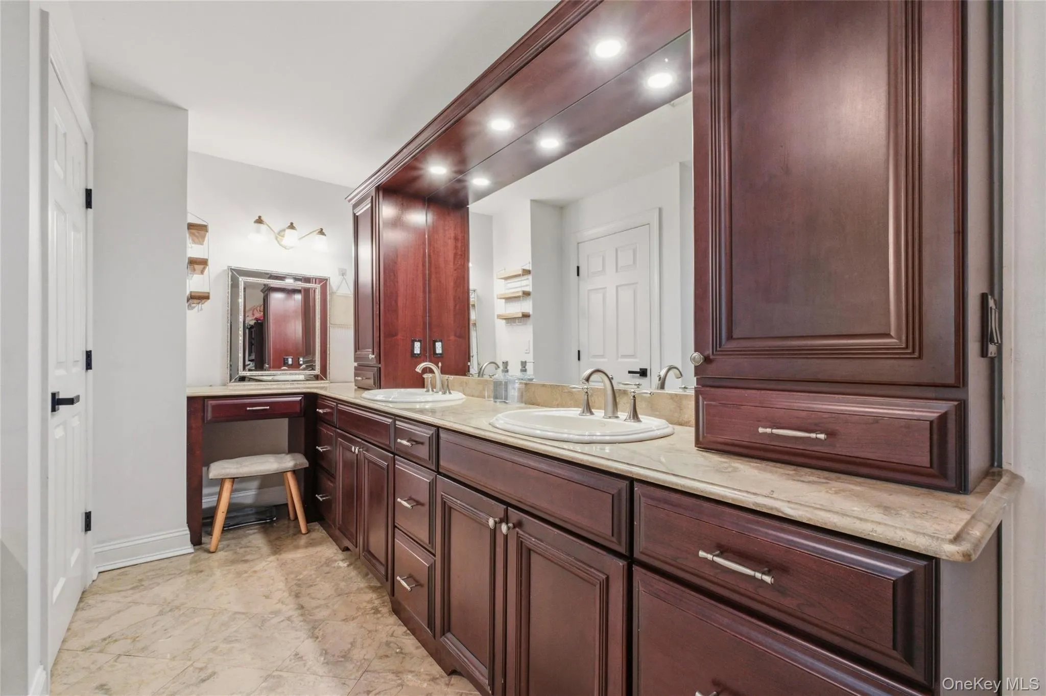 This elegant bathroom features a double-sink vanity with rich wood cabinetry, marble countertops, and abundant storage. Warm lighting and a dedicated makeup area add both luxury and functionality. This elegant bathroom features a double-sink vanity with rich wood cabinetry, marble countertops, and abundant storage. Warm lighting and a dedicated makeup area add both luxury and functionality.