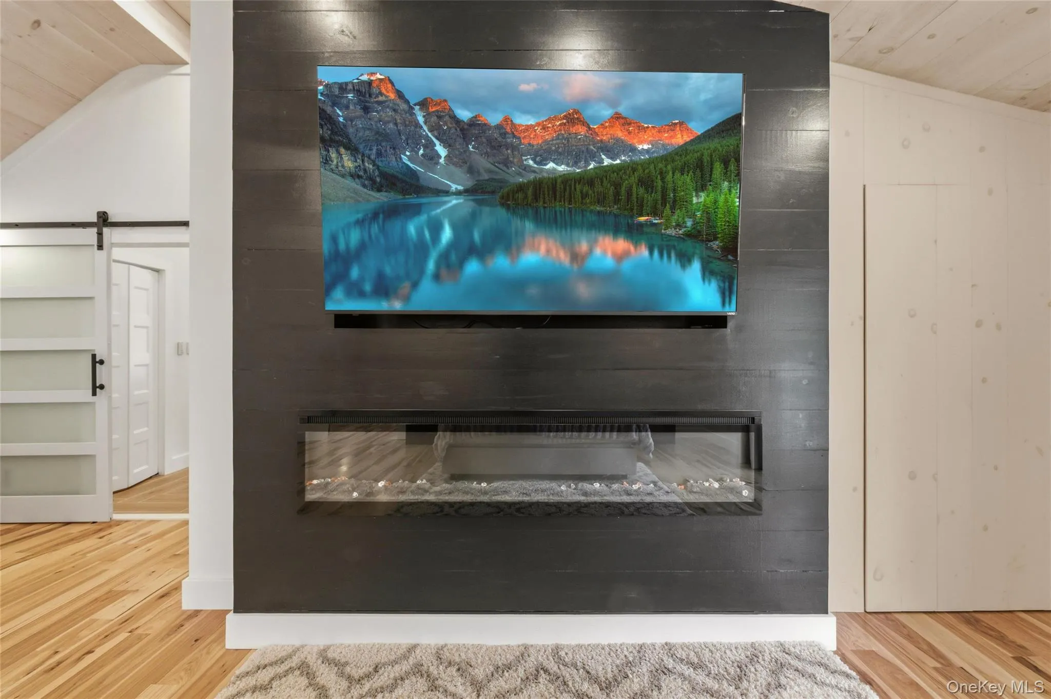 A striking black accent wall with a mounted TV and electric fireplace. A striking black accent wall with a mounted TV and electric fireplace.