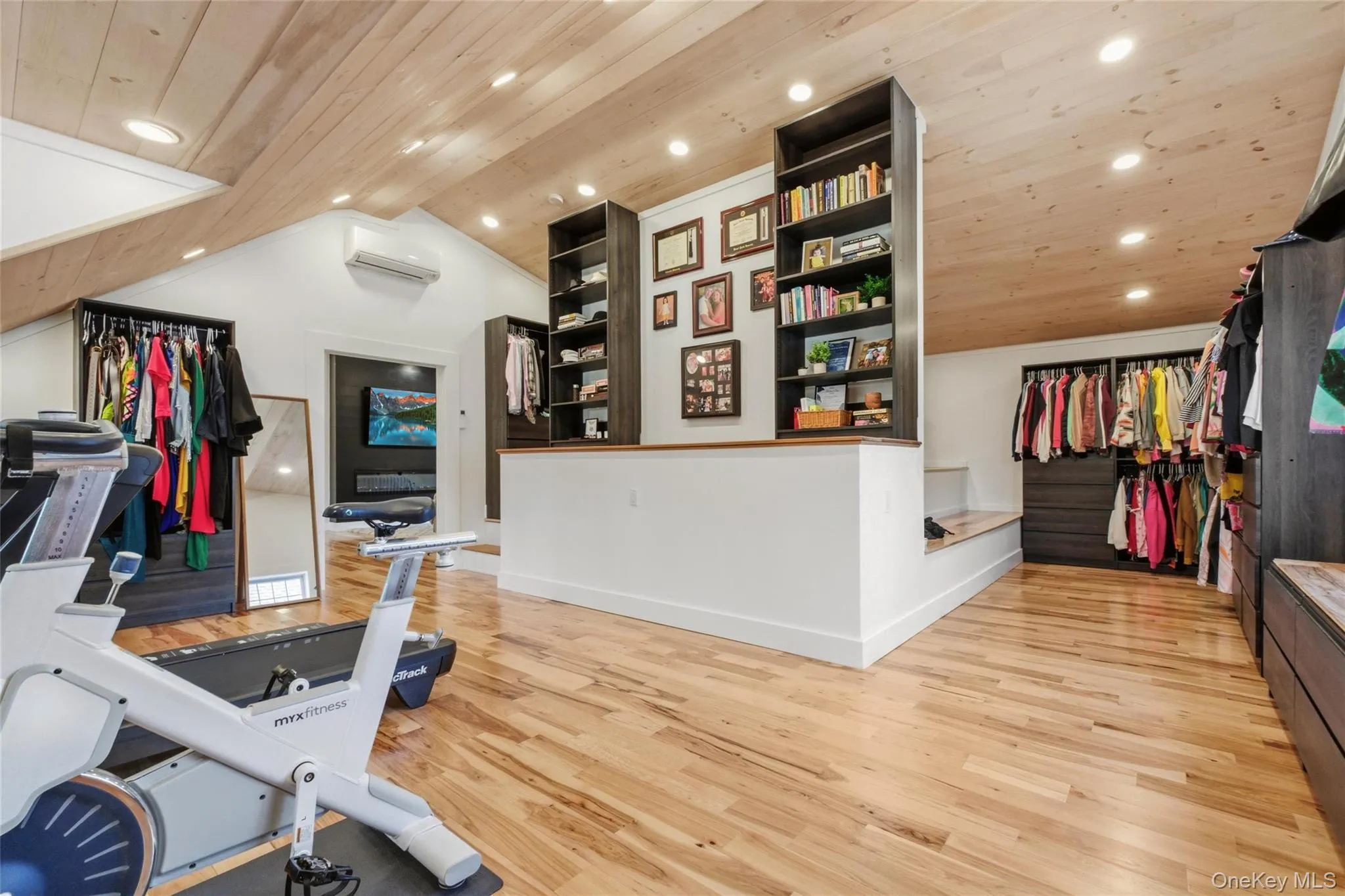 This versatile room blends a workout area, and walk-in closet into one beautifully organized layout. Wood accents and recessed lighting give the space a polished, modern feel. This versatile room blends a workout area, and walk-in closet into one beautifully organized layout. Wood accents and recessed lighting give the space a polished, modern feel.