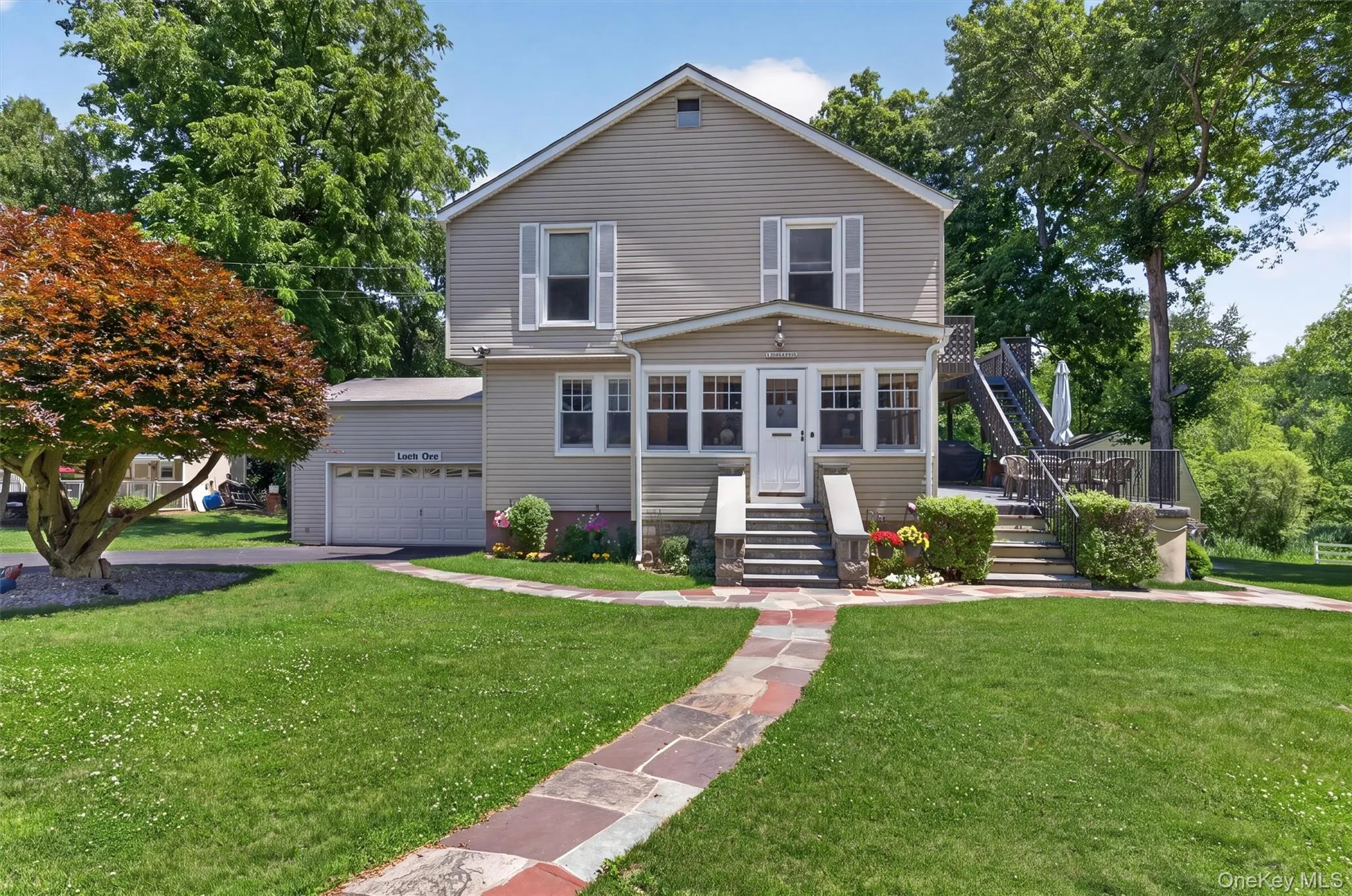 Traditional two-story residence with horizontal siding, featuring a covered front porch with multiple windows and a stone pathway leading to the entry Traditional two-story residence with horizontal siding, featuring a covered front porch with multiple windows and a stone pathway leading to the entry