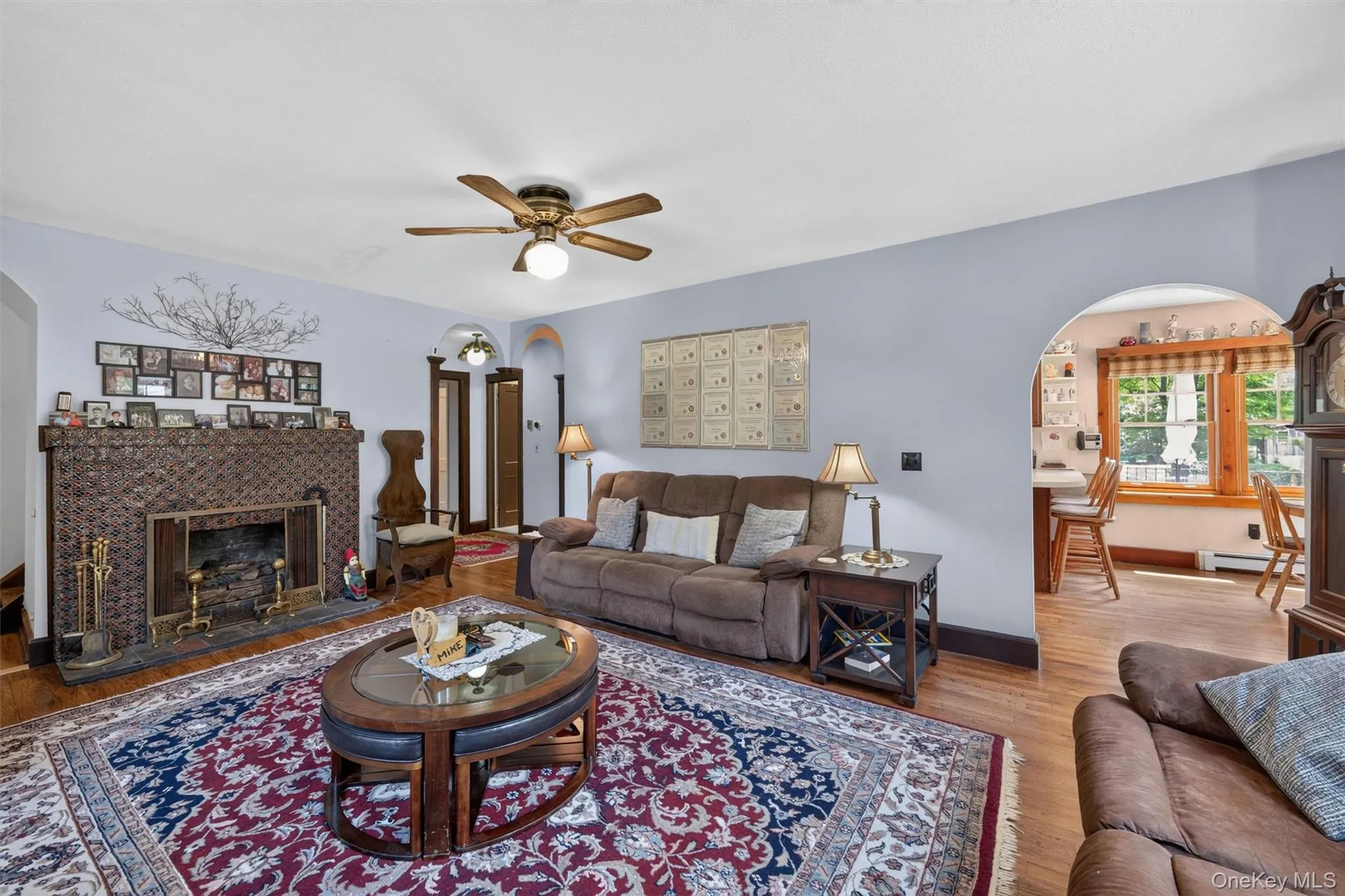 Living area featuring hardwood flooring, a ceiling fan with integrated lighting, and an arched doorway Living area featuring hardwood flooring, a ceiling fan with integrated lighting, and an arched doorway