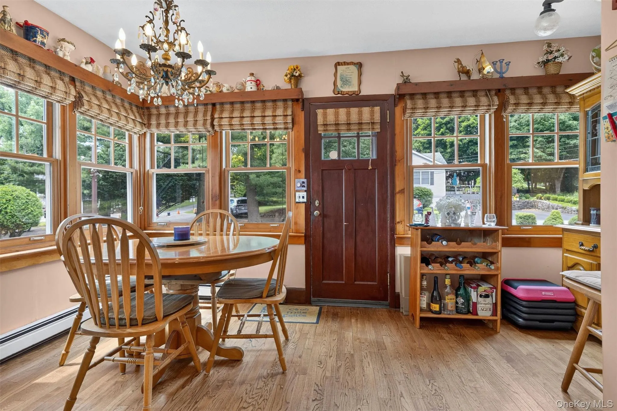 Dining area featuring wood-finish flooring, a bay window with multiple panes, and a chandelier with crystalline accents Dining area featuring wood-finish flooring, a bay window with multiple panes, and a chandelier with crystalline accents