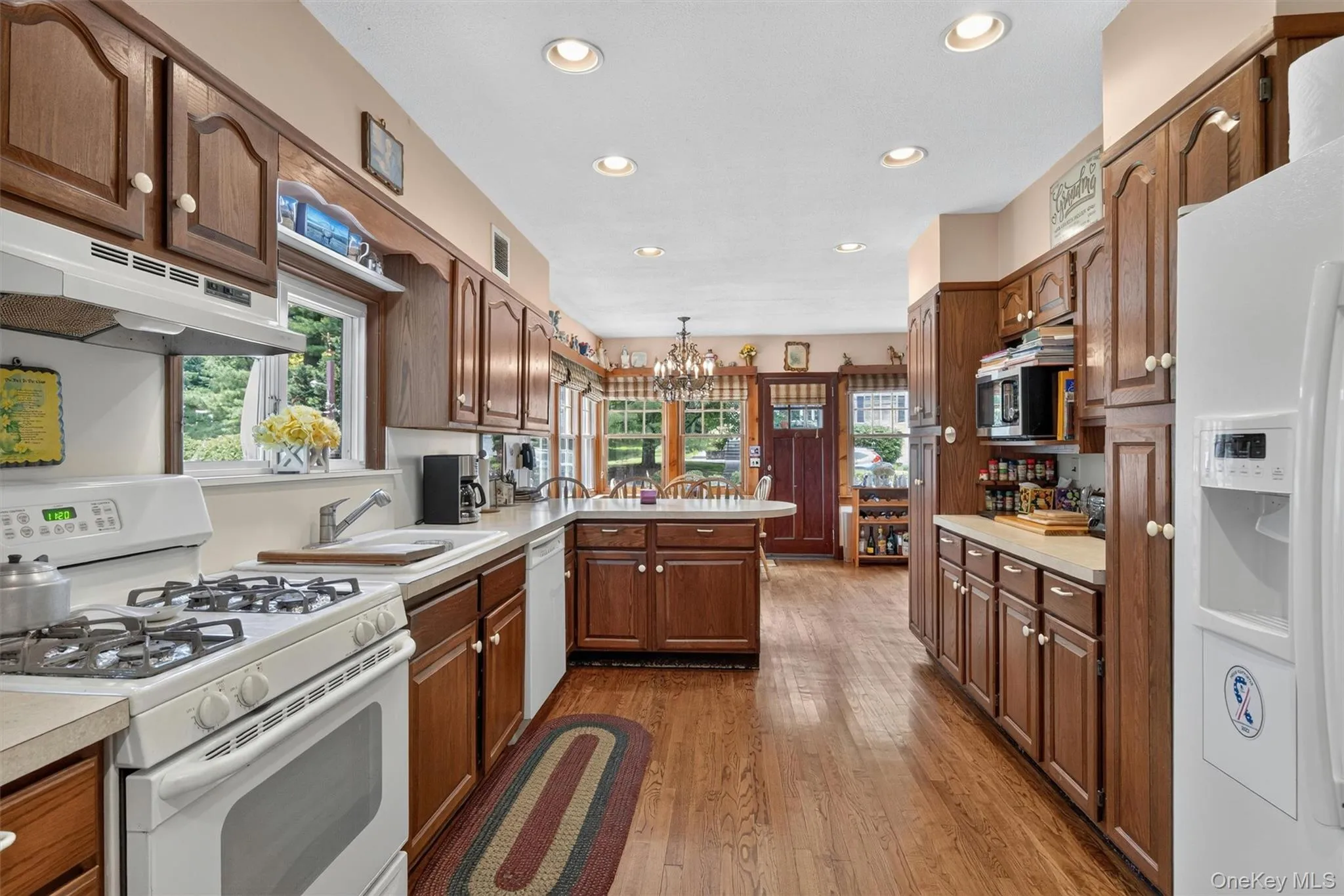 Kitchen featuring extensive wood cabinetry, wood-finish flooring, recessed lighting, and a window above the sink Kitchen featuring extensive wood cabinetry, wood-finish flooring, recessed lighting, and a window above the sink