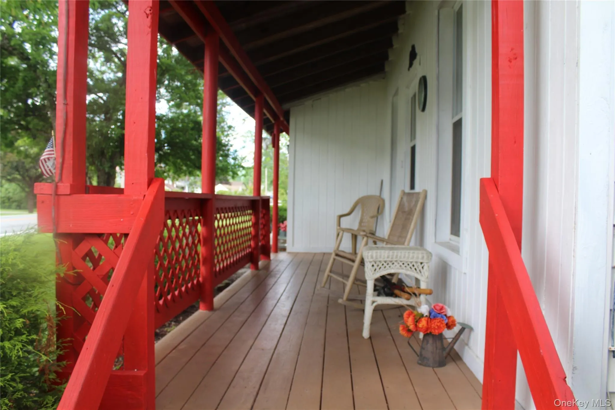 Covered front porch featuring a wood-finish floor and white vertical siding Covered front porch featuring a wood-finish floor and white vertical siding