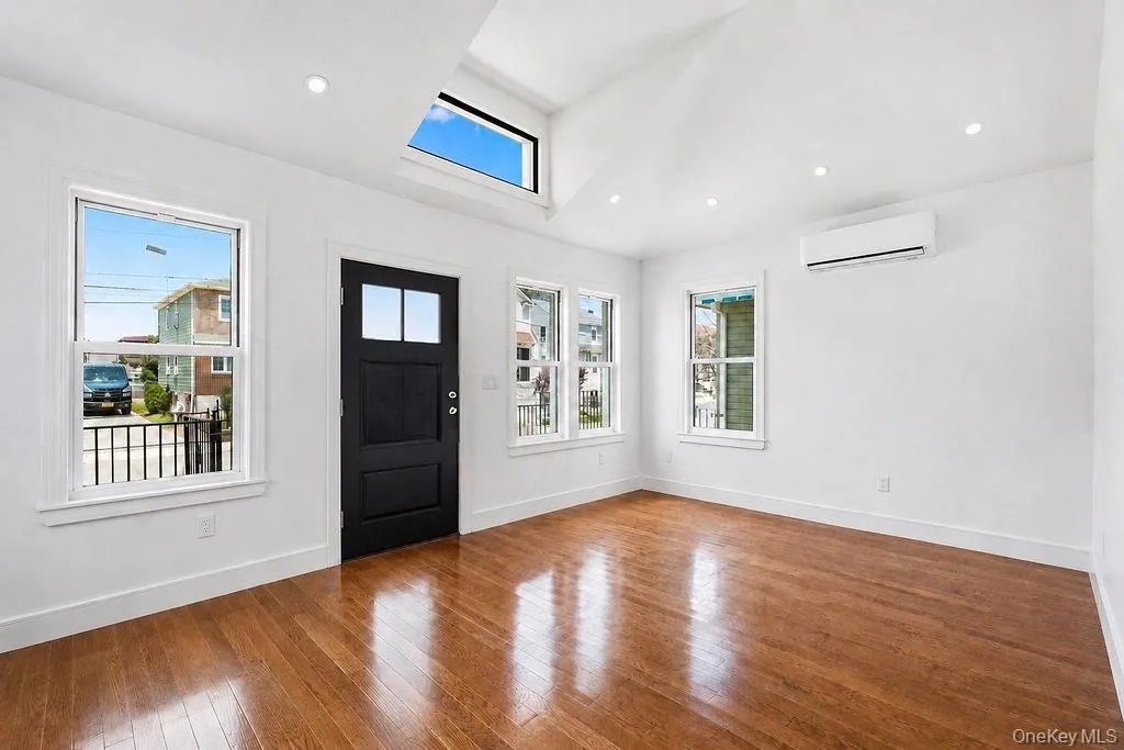 Entry area featuring a dark paneled door with glass inserts, wood-finish flooring, and white walls Entry area featuring a dark paneled door with glass inserts, wood-finish flooring, and white walls