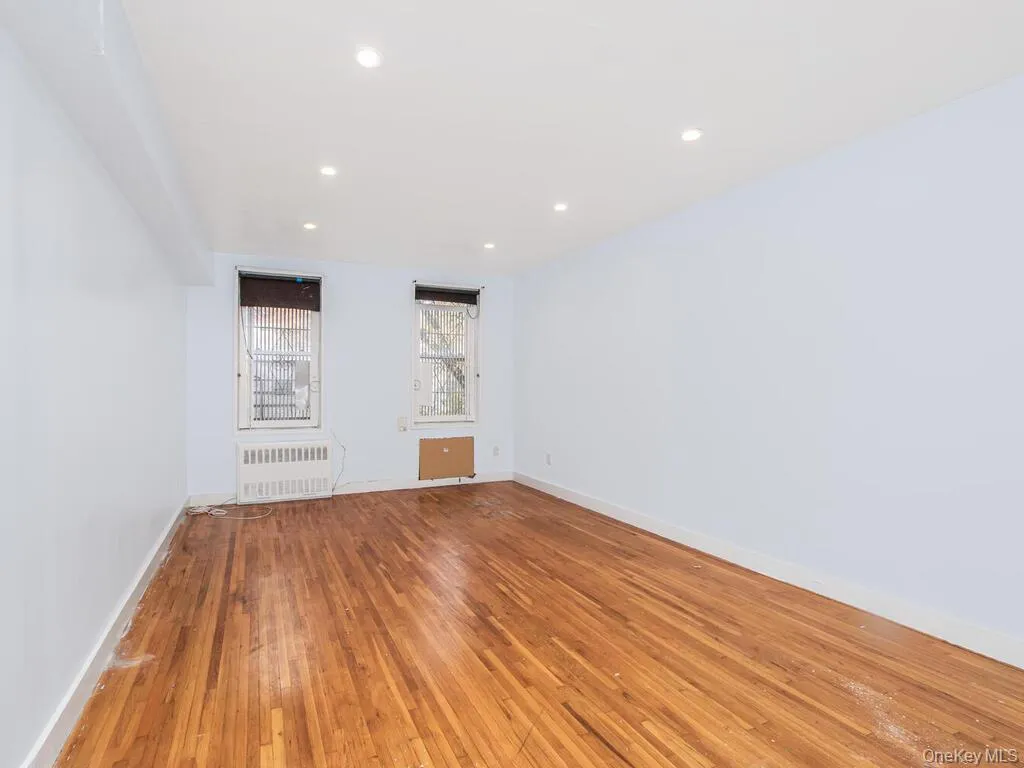 Empty room featuring light wood-style floors, radiator, and recessed lighting Empty room featuring light wood-style floors, radiator, and recessed lighting