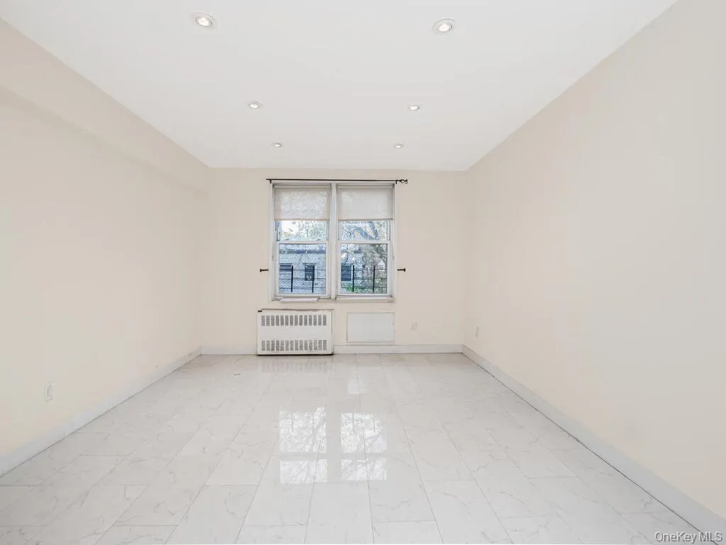 Unfurnished room with radiator heating unit, light marble finish flooring, and recessed lighting Unfurnished room with radiator heating unit, light marble finish flooring, and recessed lighting