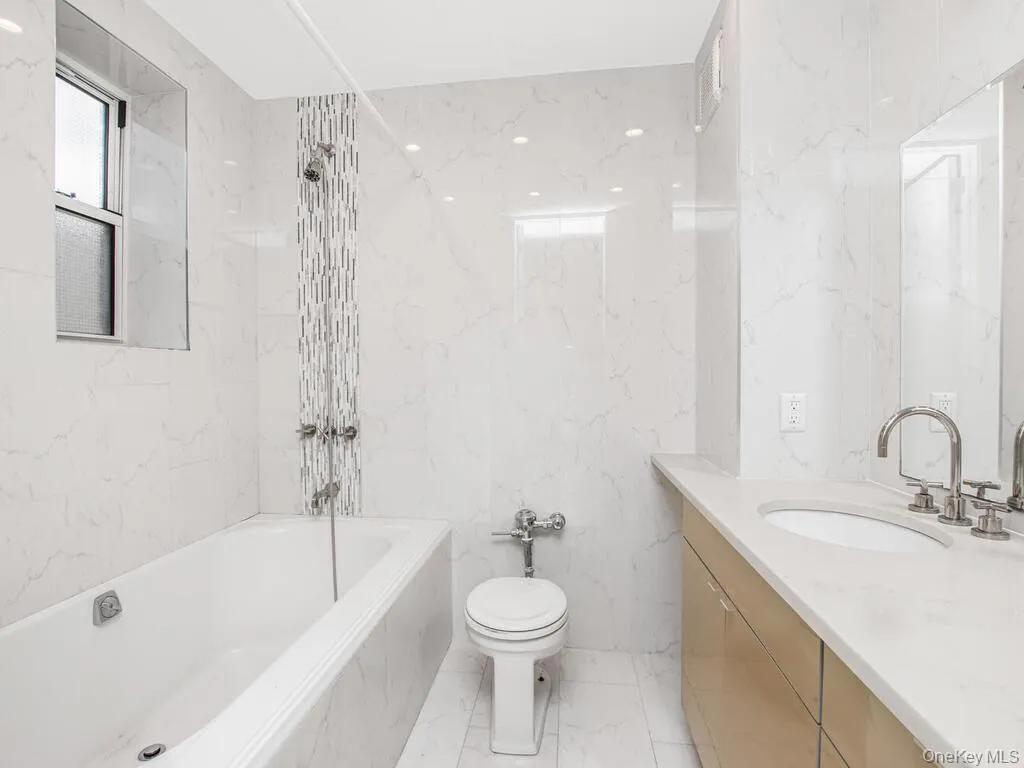 Full bath featuring vanity, stone wall, light marble finish flooring, a combined bath / shower with marble appearance, and tile walls Full bath featuring vanity, stone wall, light marble finish flooring, a combined bath / shower with marble appearance, and tile walls