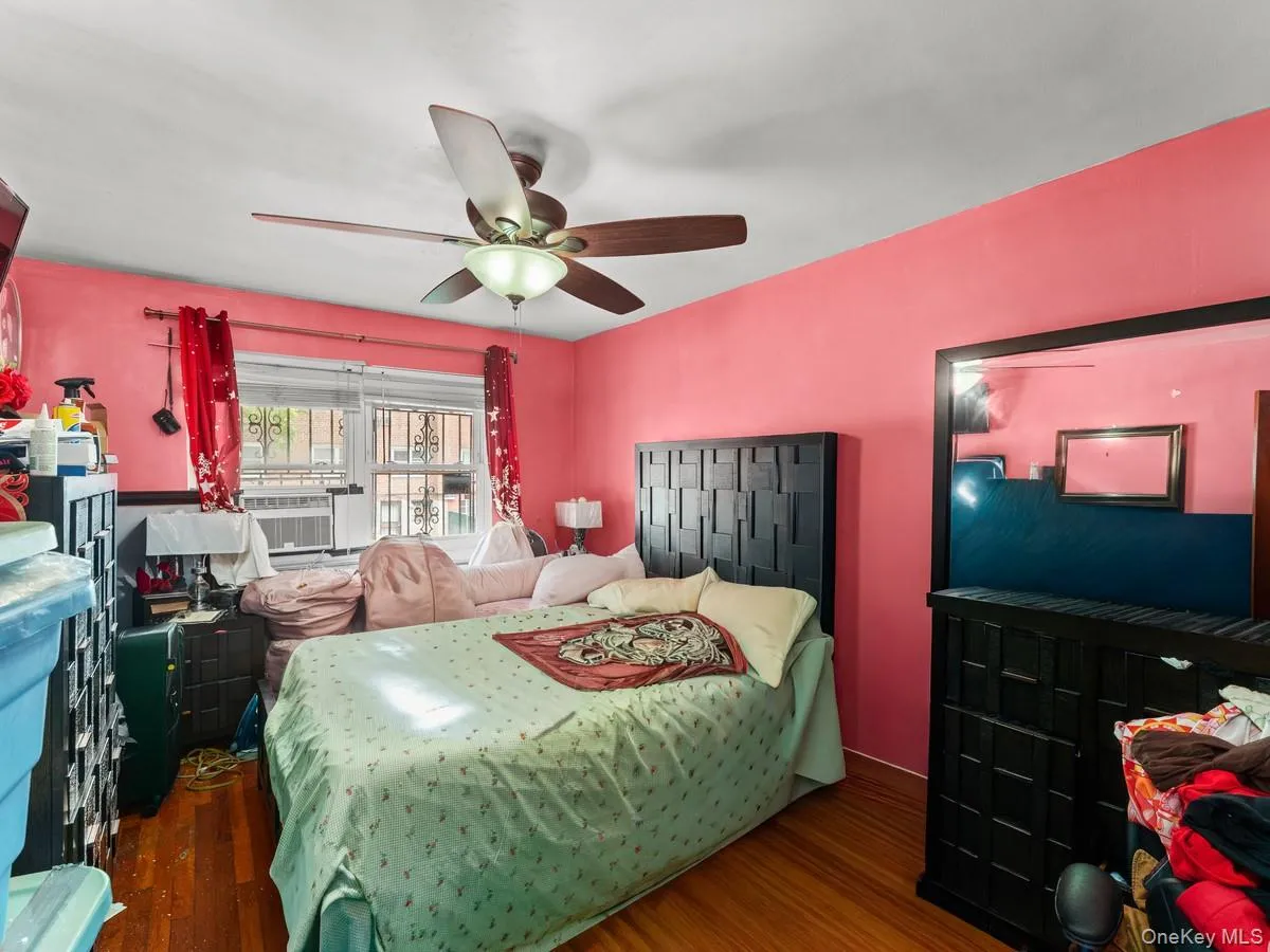 Bedroom 2, 1st. Floor featuring wood-finish flooring, a ceiling fan with integrated lighting, and a window with security bars Bedroom 2, 1st. Floor featuring wood-finish flooring, a ceiling fan with integrated lighting, and a window with security bars