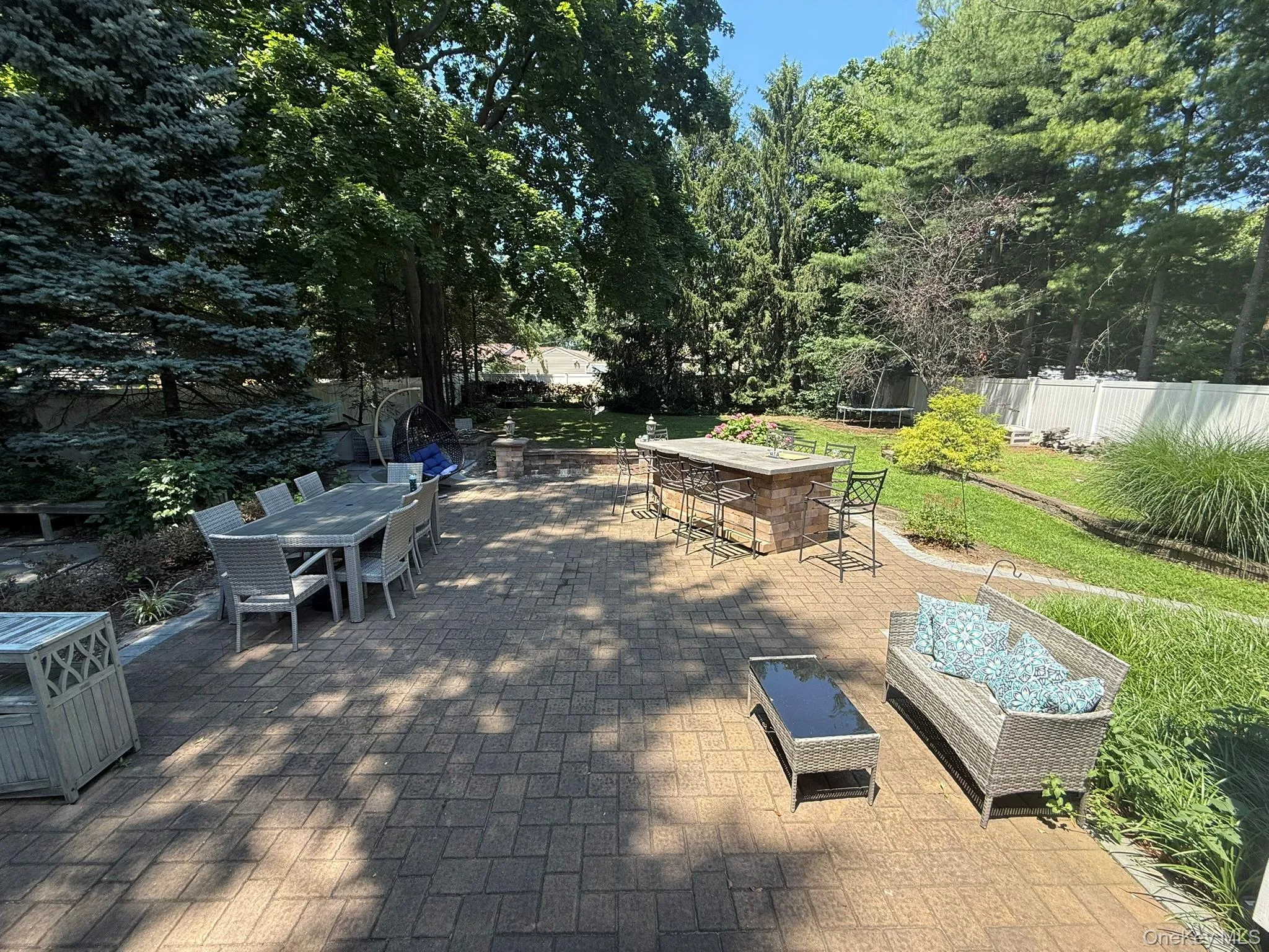 Expansive paver patio with a built-in outdoor kitchen island and perimeter landscaping, View from den doors Expansive paver patio with a built-in outdoor kitchen island and perimeter landscaping, View from den doors