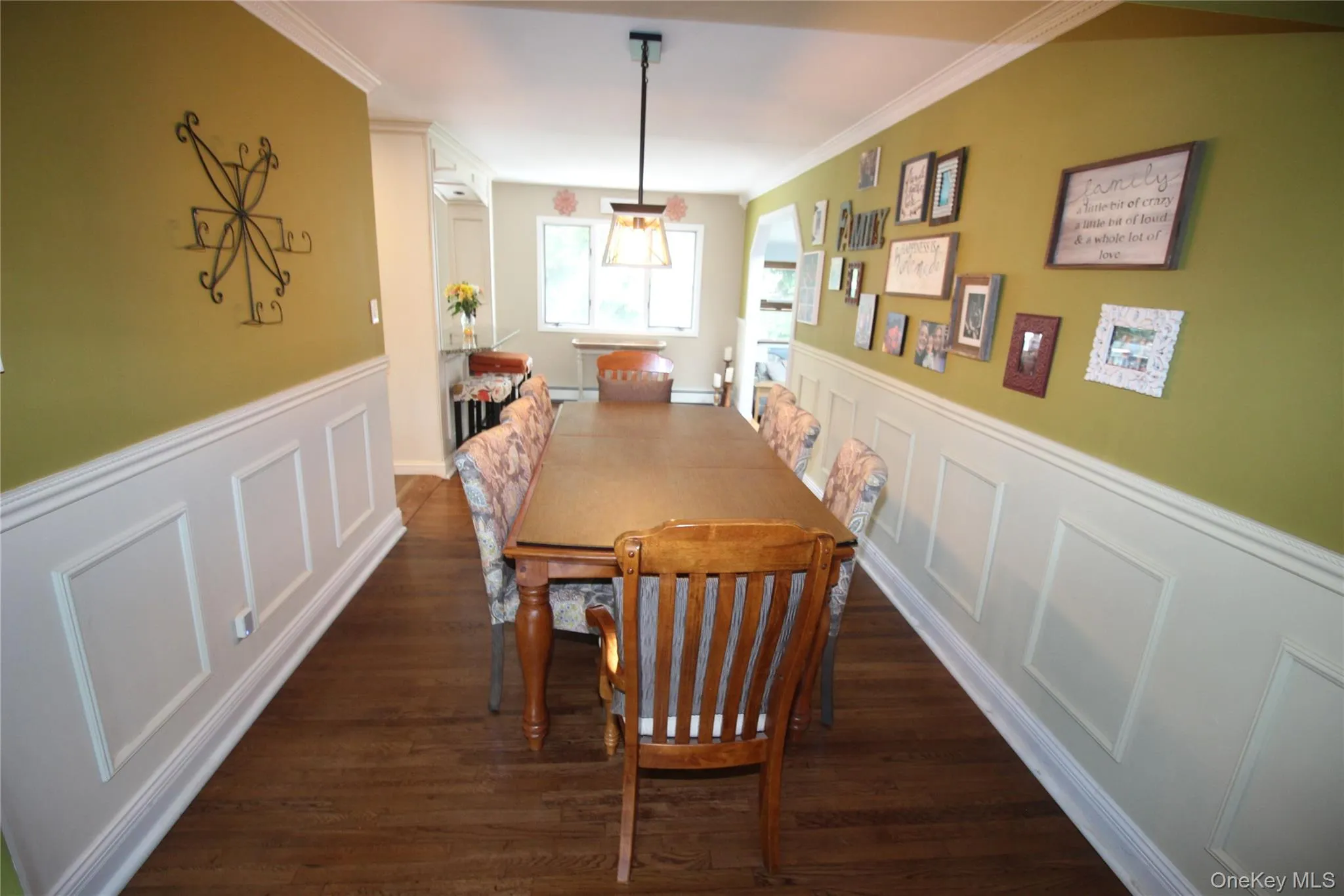 Dining area featuring wood-finish flooring, wainscoting, and crown molding Dining area featuring wood-finish flooring, wainscoting, and crown molding