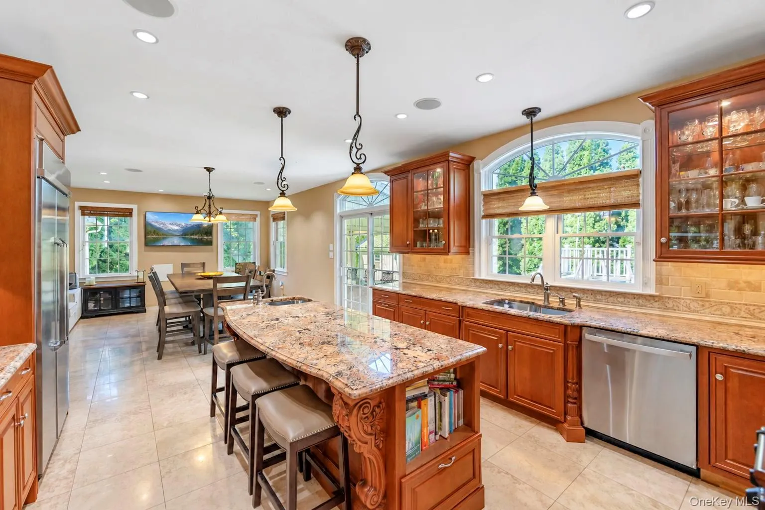 Kitchen featuring a large island with stone countertop, stainless steel appliances, recessed ceiling lights, and arched windows Kitchen featuring a large island with stone countertop, stainless steel appliances, recessed ceiling lights, and arched windows