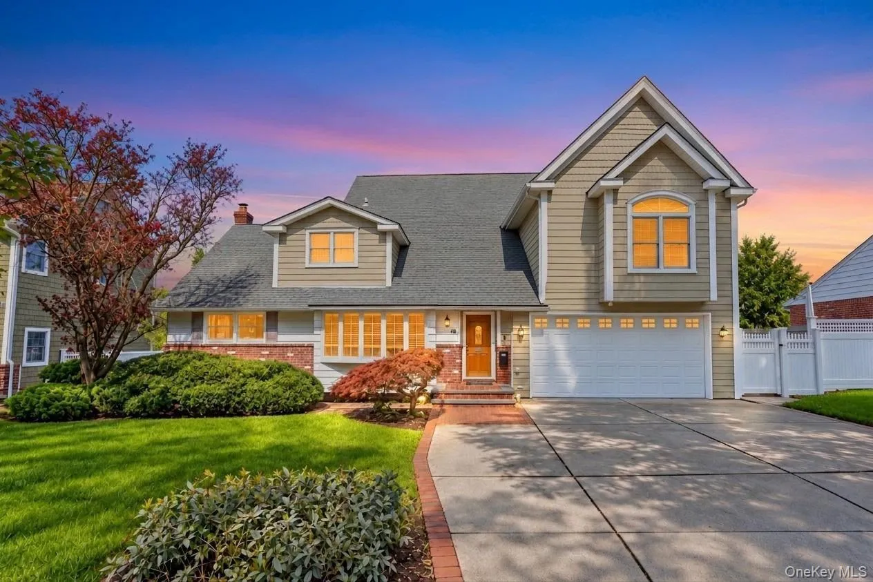 Traditional-style home featuring a two-car garage, brick paver walkway, dormer windows, and a white picket fence Traditional-style home featuring a two-car garage, brick paver walkway, dormer windows, and a white picket fence