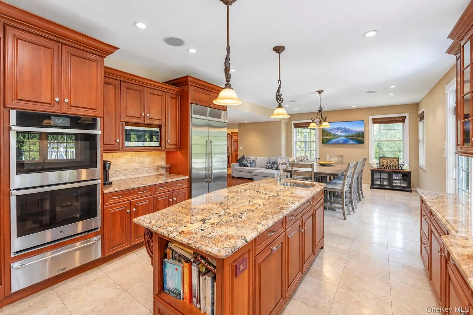 Kitchen featuring wood cabinetry, stainless steel appliances, a large center island with a sink, and granite countertops Kitchen featuring wood cabinetry, stainless steel appliances, a large center island with a sink, and granite countertops