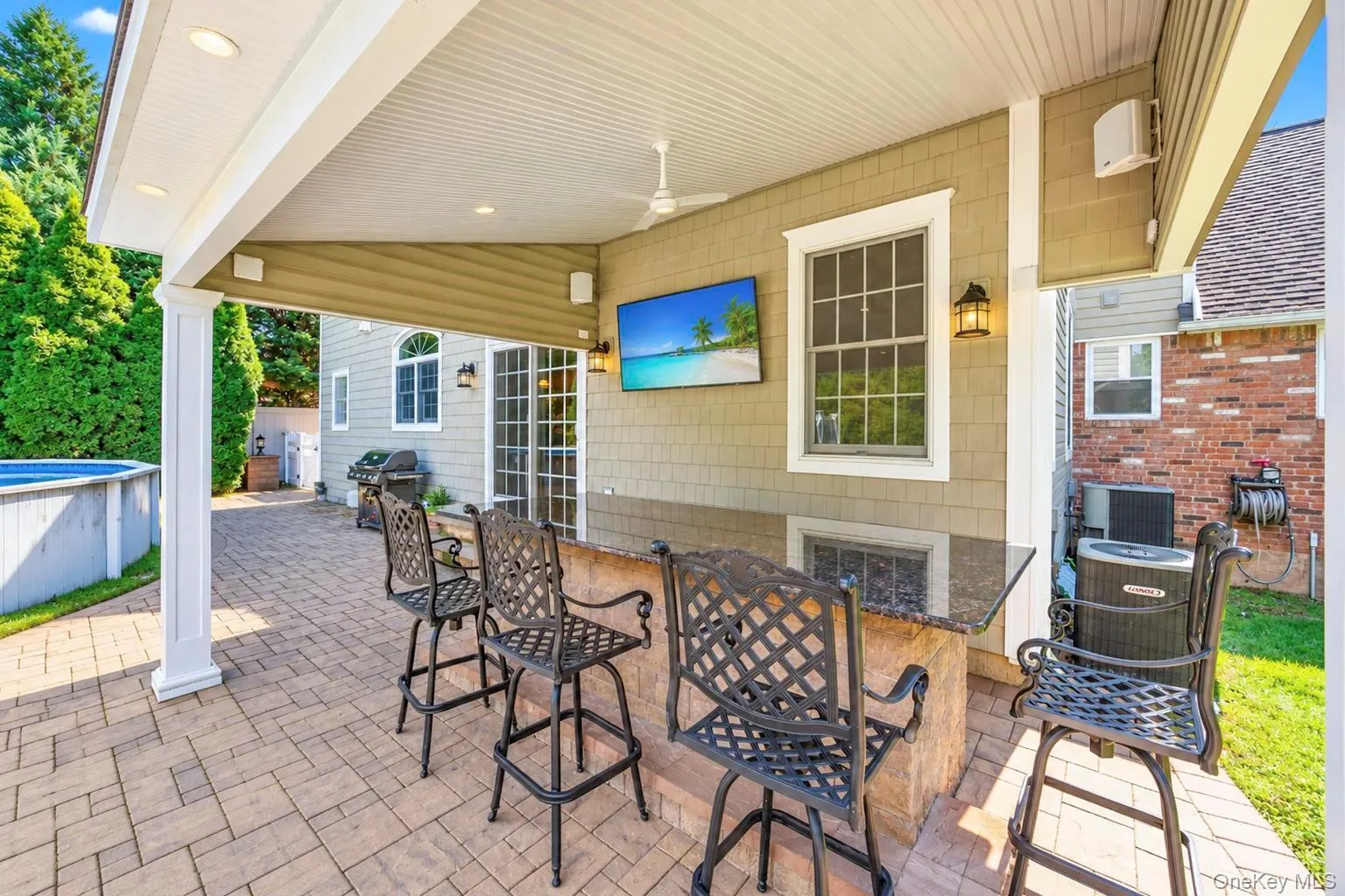 Covered outdoor patio featuring recessed lighting, a ceiling fan, and a built-in bar with a dark stone countertop Covered outdoor patio featuring recessed lighting, a ceiling fan, and a built-in bar with a dark stone countertop