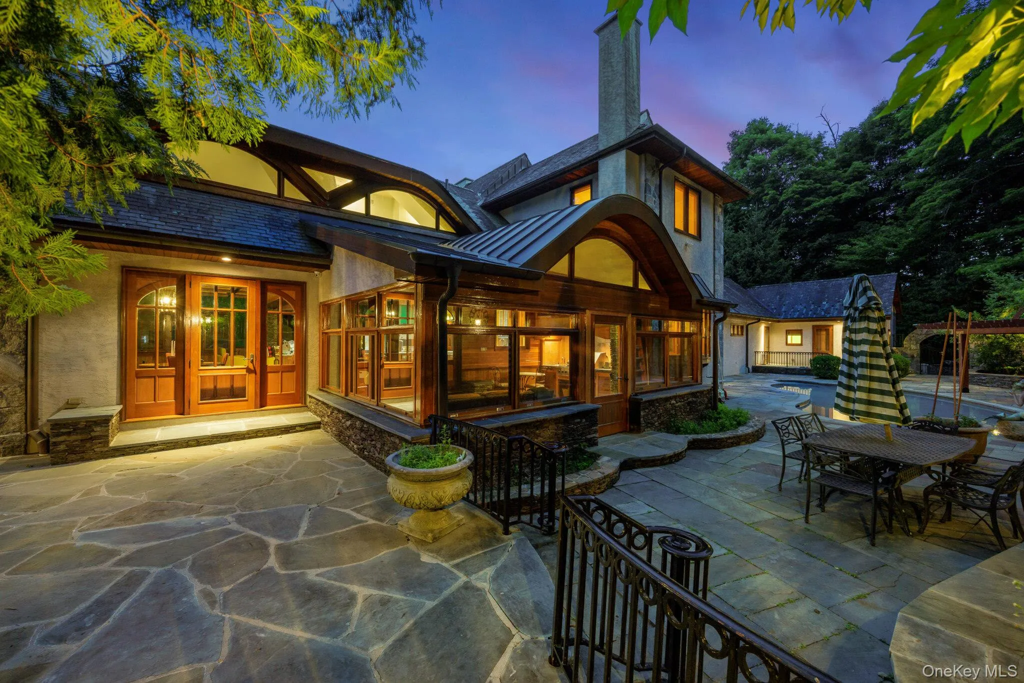 Custom architectural design featuring a stone exterior, wood-framed windows, and curved roofing accents Custom architectural design featuring a stone exterior, wood-framed windows, and curved roofing accents