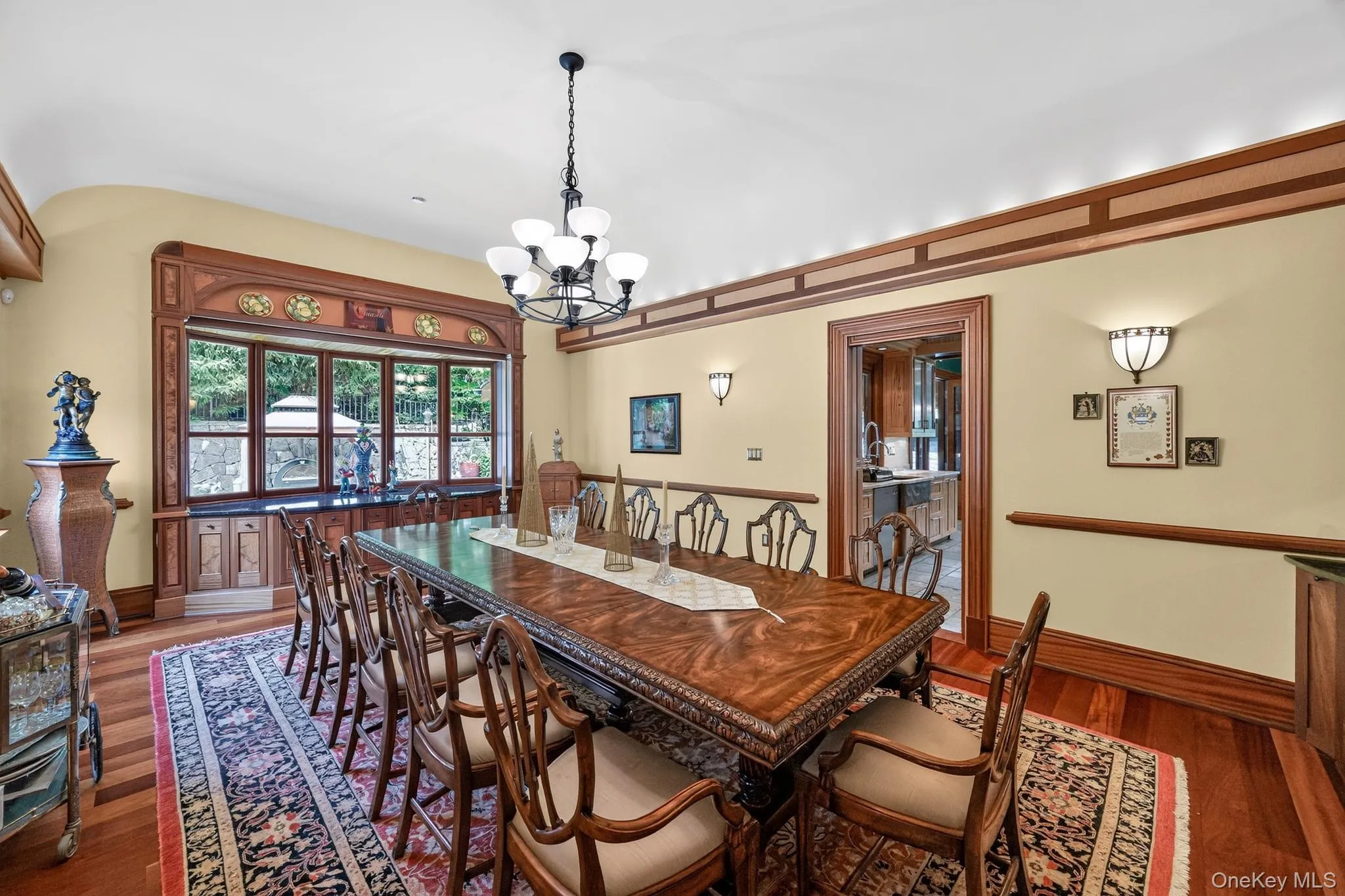 Formal dining area featuring hardwood flooring, a multi-pane bay window with intricate wood trim, and a decorative chandelier Formal dining area featuring hardwood flooring, a multi-pane bay window with intricate wood trim, and a decorative chandelier