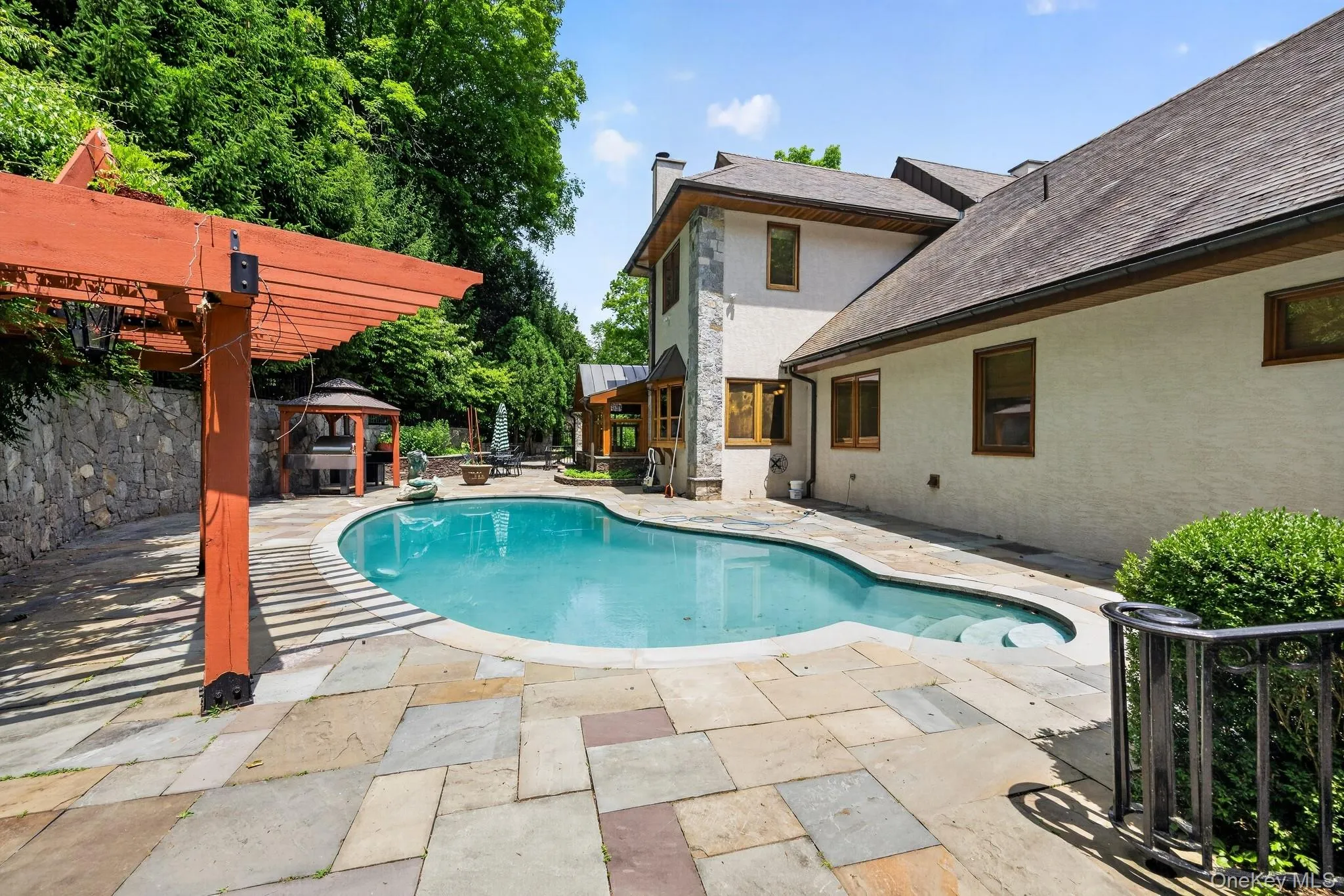 Curved swimming pool bordered by extensive flagstone patio Curved swimming pool bordered by extensive flagstone patio