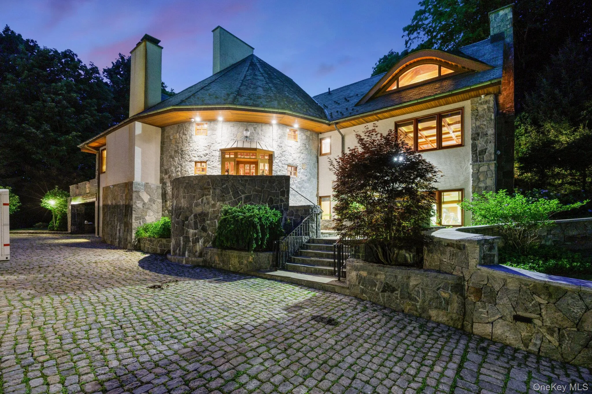 Stone and stucco exterior featuring multiple gables and a rounded turret with a slate roof Stone and stucco exterior featuring multiple gables and a rounded turret with a slate roof