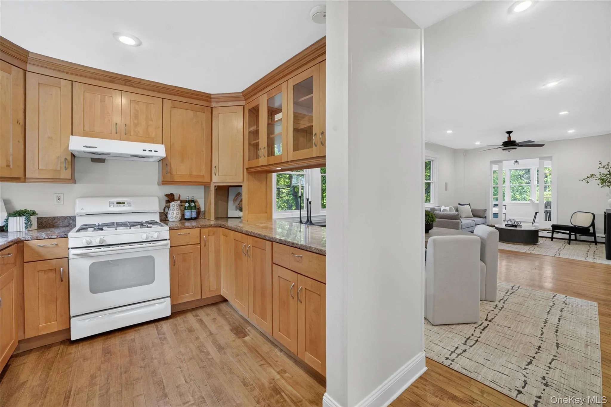 Kitchen featuring natural wood cabinetry, stone countertops, and wood-finish flooring Kitchen featuring natural wood cabinetry, stone countertops, and wood-finish flooring