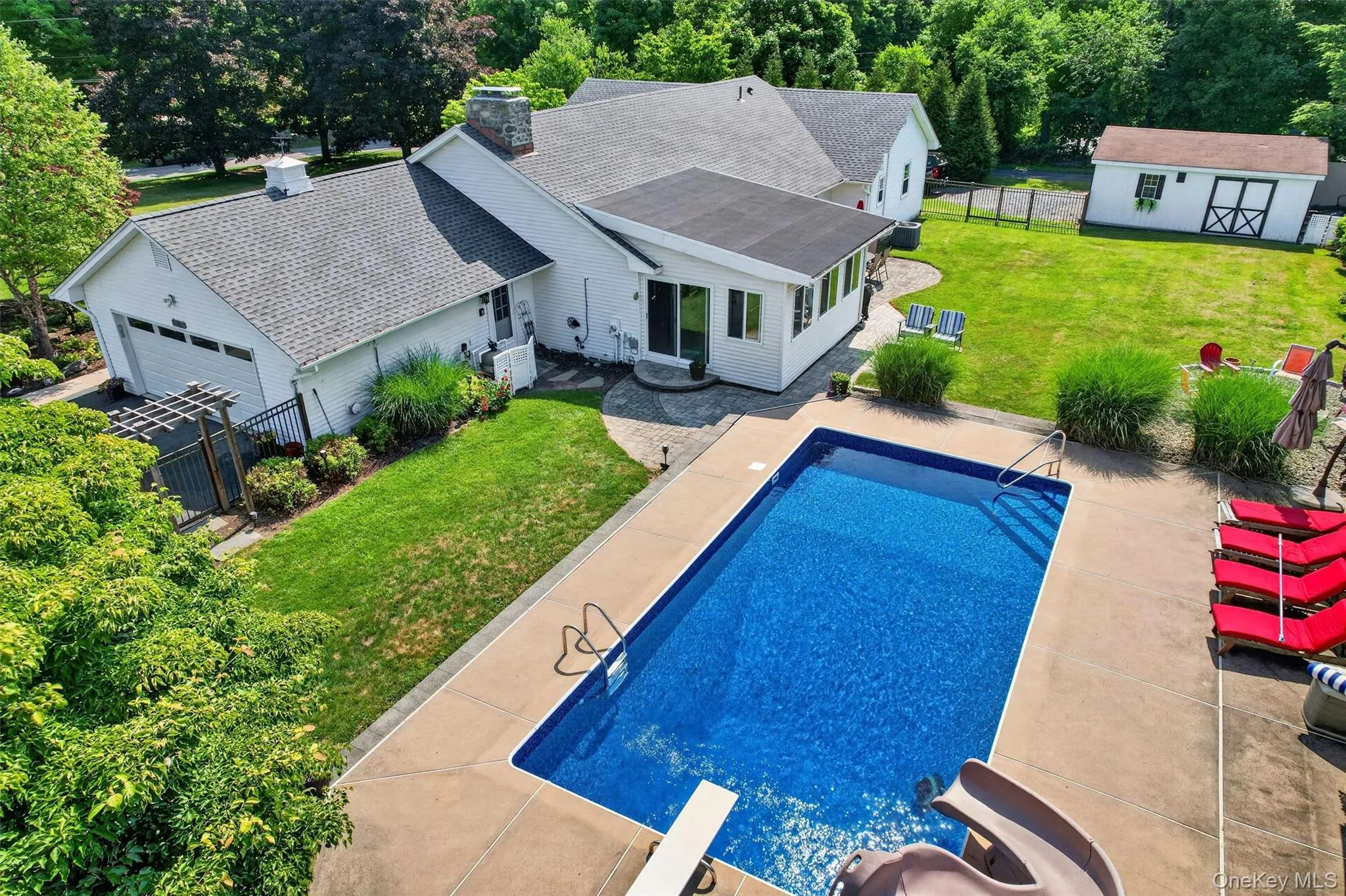 An aerial look at the backyard retreat, featuring the pool, patios, lawn space, privacy fencing, and detached garage. An aerial look at the backyard retreat, featuring the pool, patios, lawn space, privacy fencing, and detached garage.