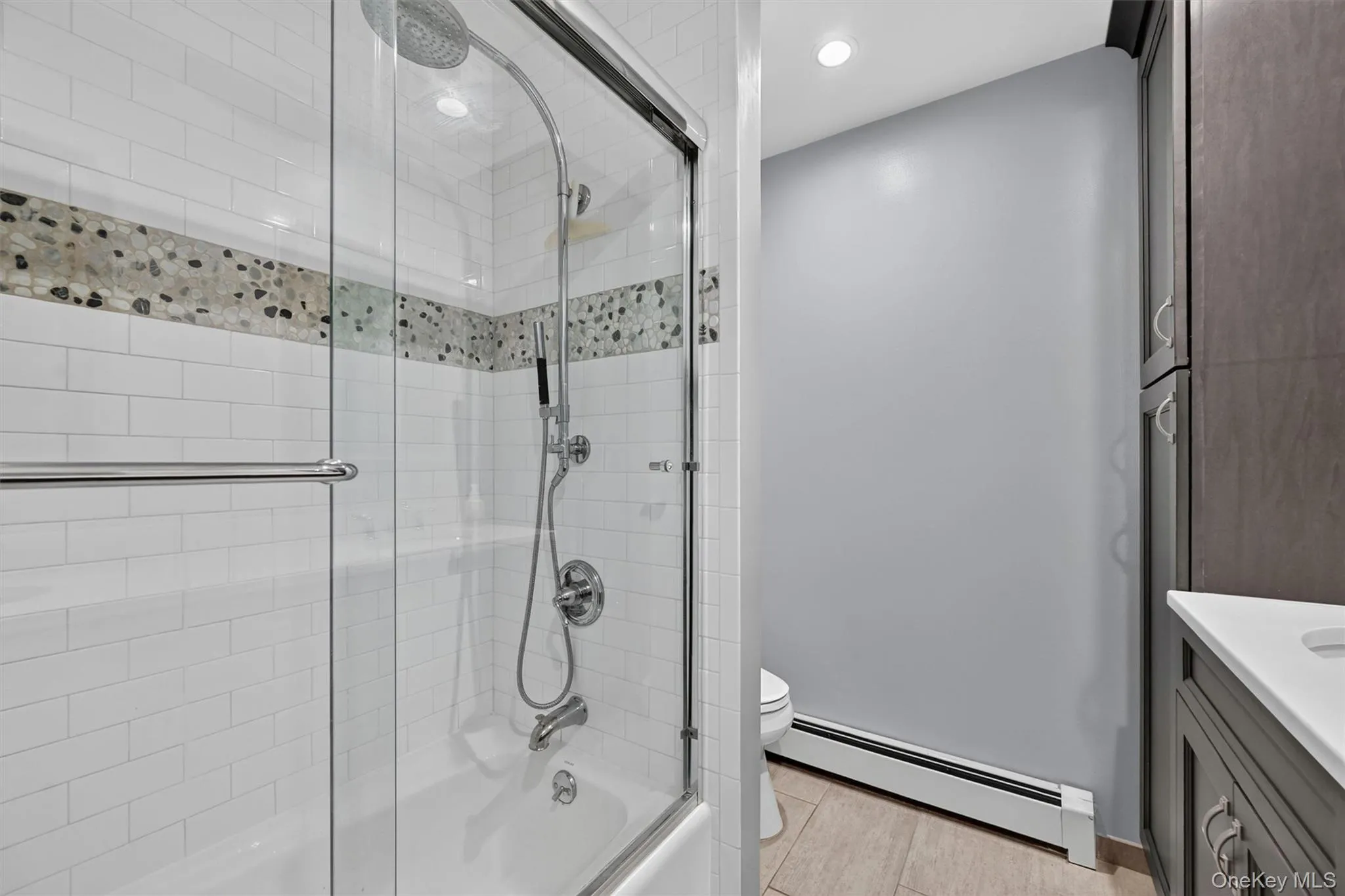 A glass-enclosed tub/shower with classic tile detail completes the updated hall bath serving the bedroom side of the home. A glass-enclosed tub/shower with classic tile detail completes the updated hall bath serving the bedroom side of the home.