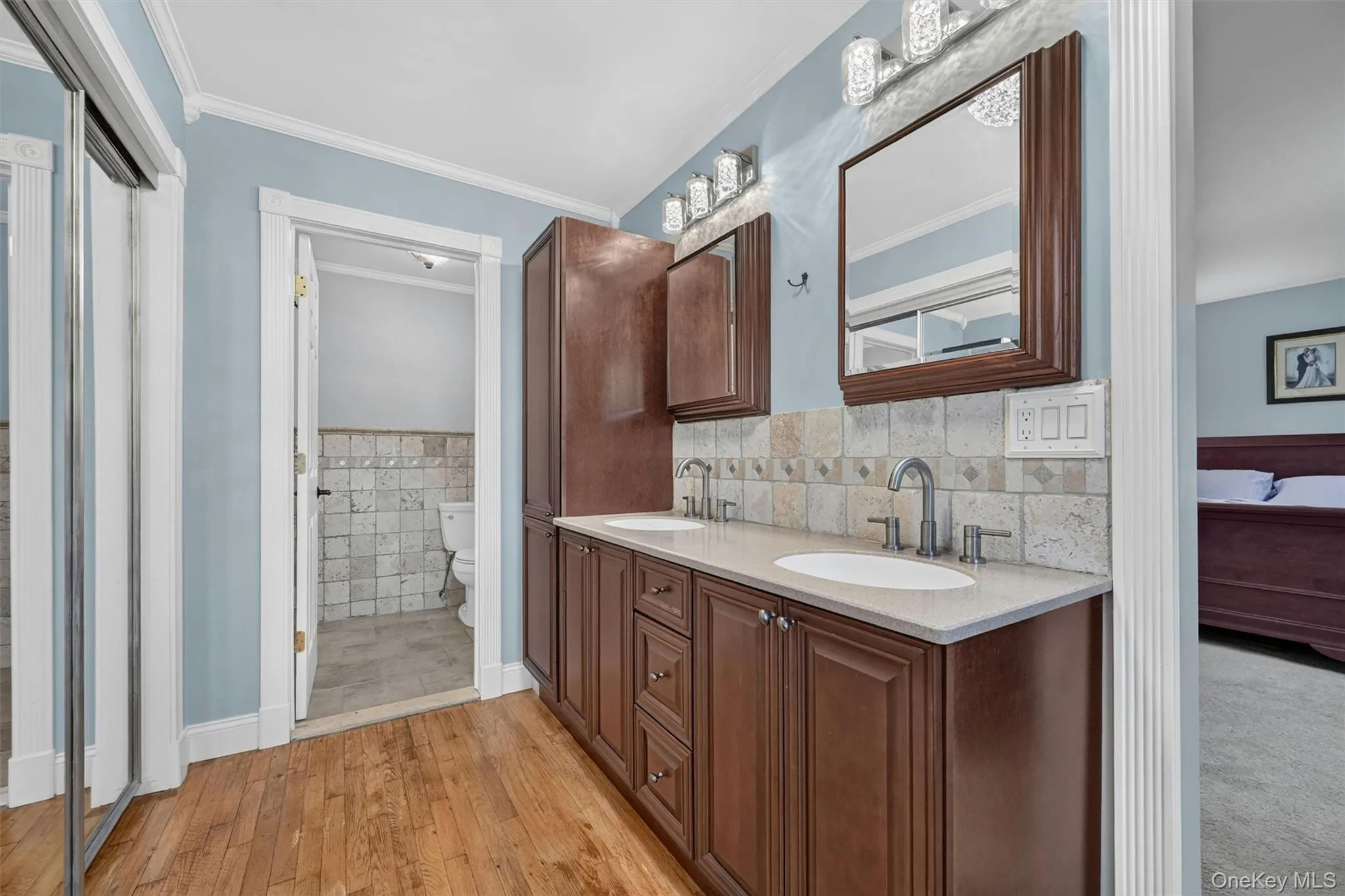 The updated en suite bath features tasteful neutral finishes, dual sinks, warm cabinetry, and closet access within the bath area. The updated en suite bath features tasteful neutral finishes, dual sinks, warm cabinetry, and closet access within the bath area.
