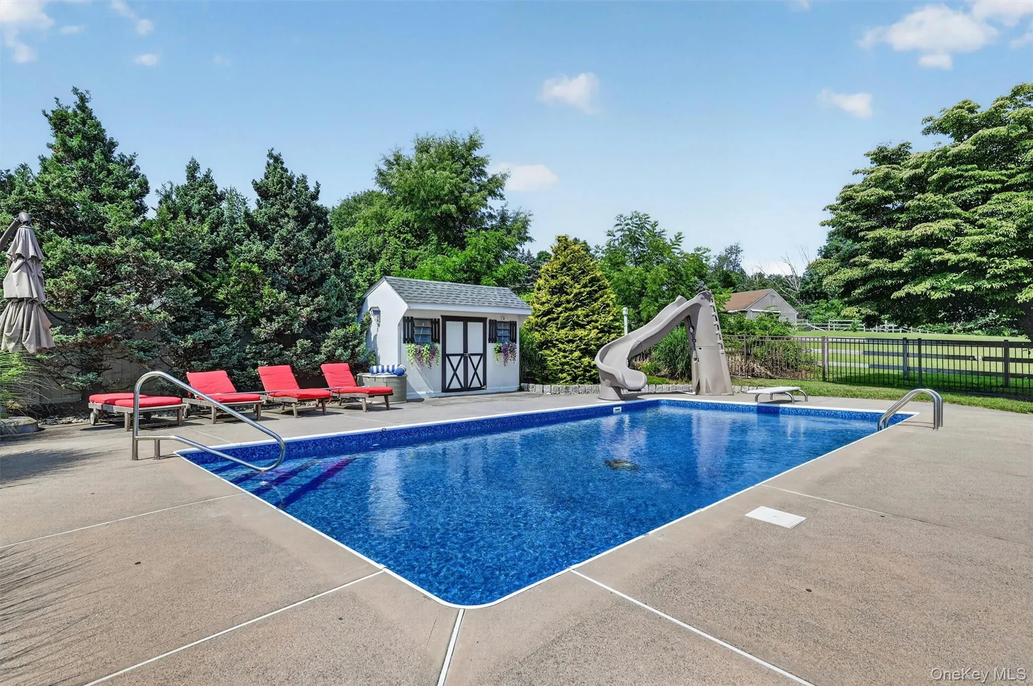 The inground pool features a new liner, generous surrounding patio space, nearby lounge seating, and a pool shed for convenient storage. The inground pool features a new liner, generous surrounding patio space, nearby lounge seating, and a pool shed for convenient storage.