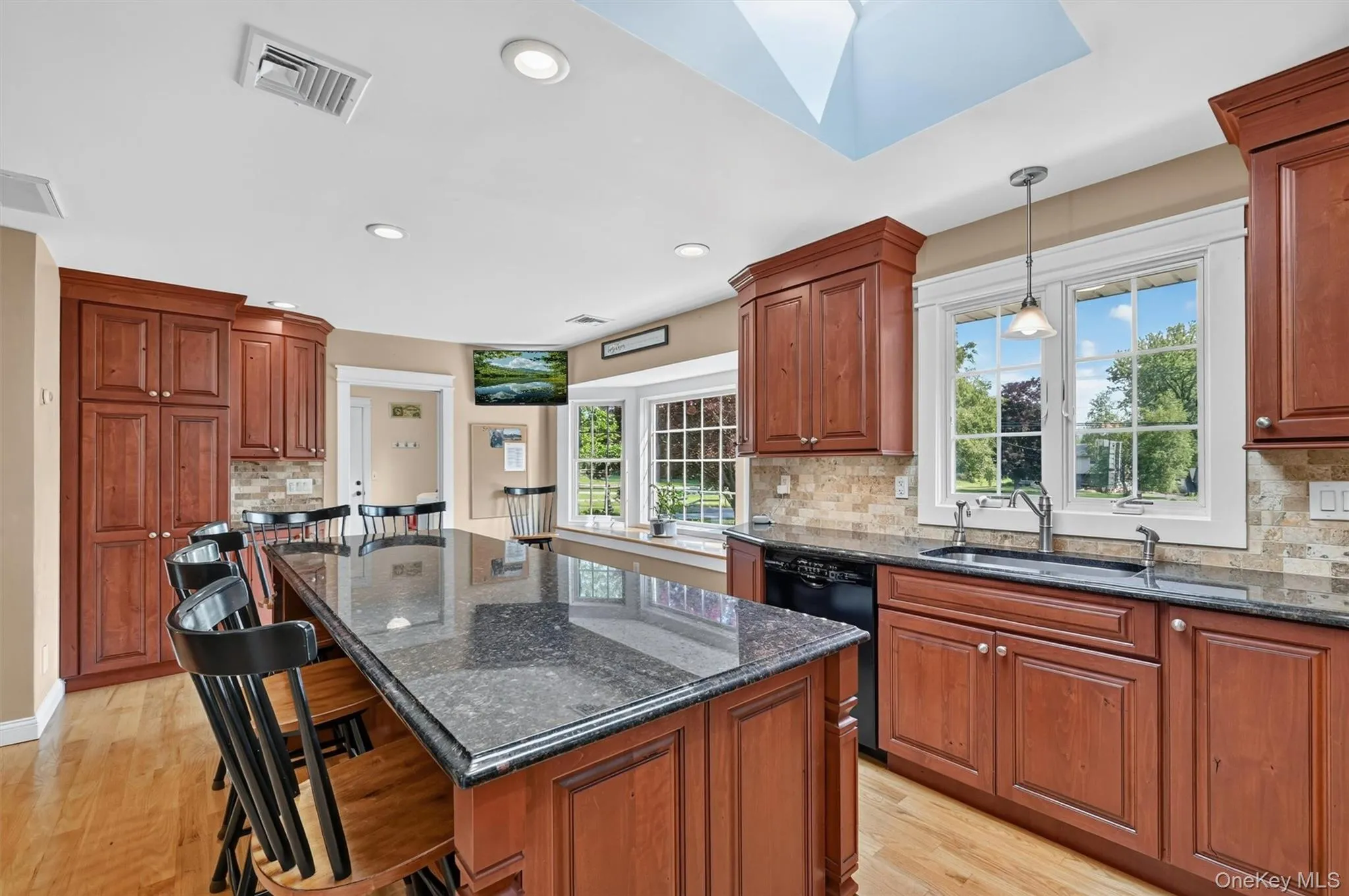 The updated chef’s kitchen is bright and inviting, with granite countertops, rich wood cabinetry, a skylight above, and a large island with seating for six. The updated chef’s kitchen is bright and inviting, with granite countertops, rich wood cabinetry, a skylight above, and a large island with seating for six.